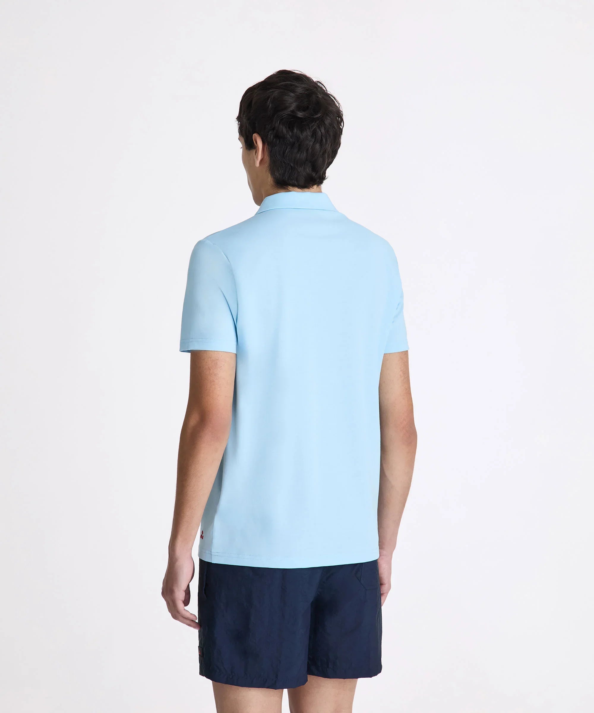 Uomo di spalle con polo celeste e pantaloncini blu, abbigliamento casual estivo