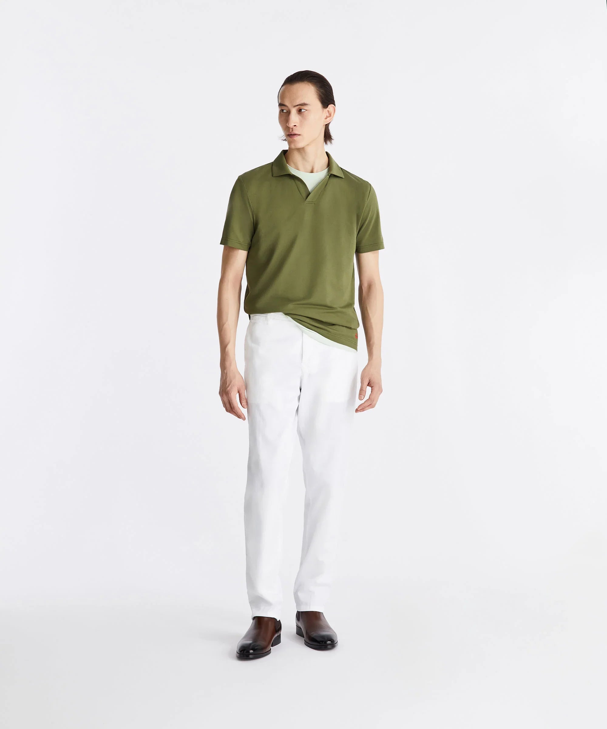 Modello uomo con polo verde, pantaloni bianchi eleganti e scarpe marroni, moda primavera estate