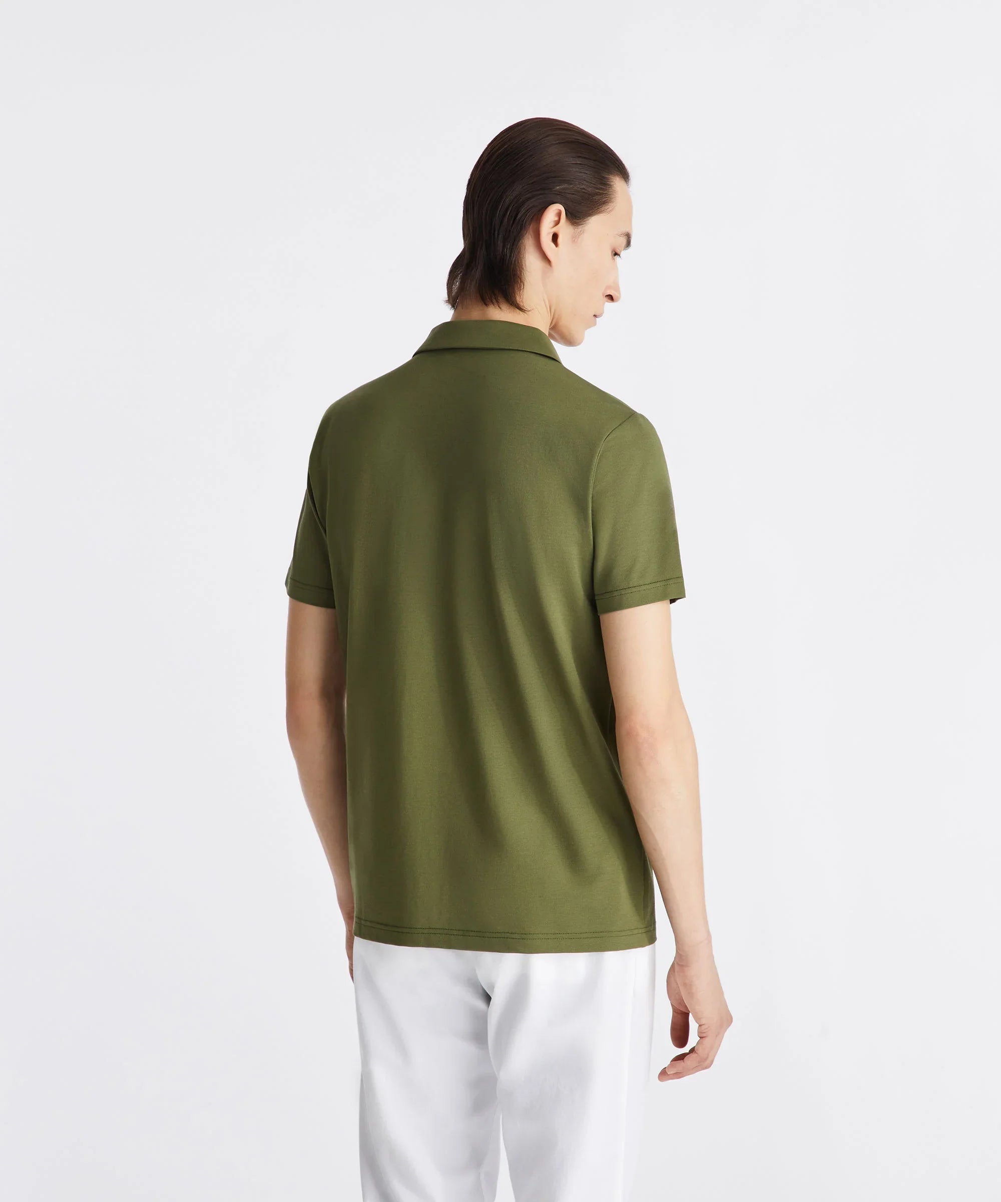 Uomo di spalle con polo verde e pantaloni bianchi, abbigliamento casual elegante