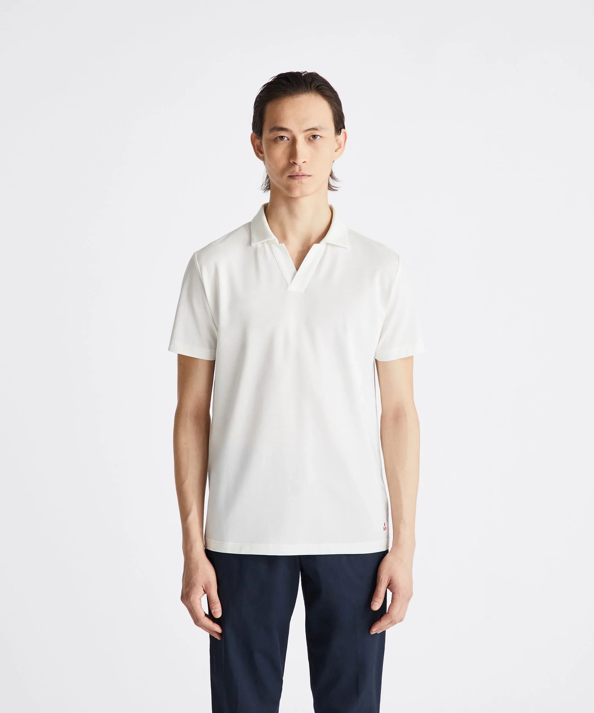 Modello uomo indossa polo bianca a manica corta, stile casual, su sfondo neutro.
