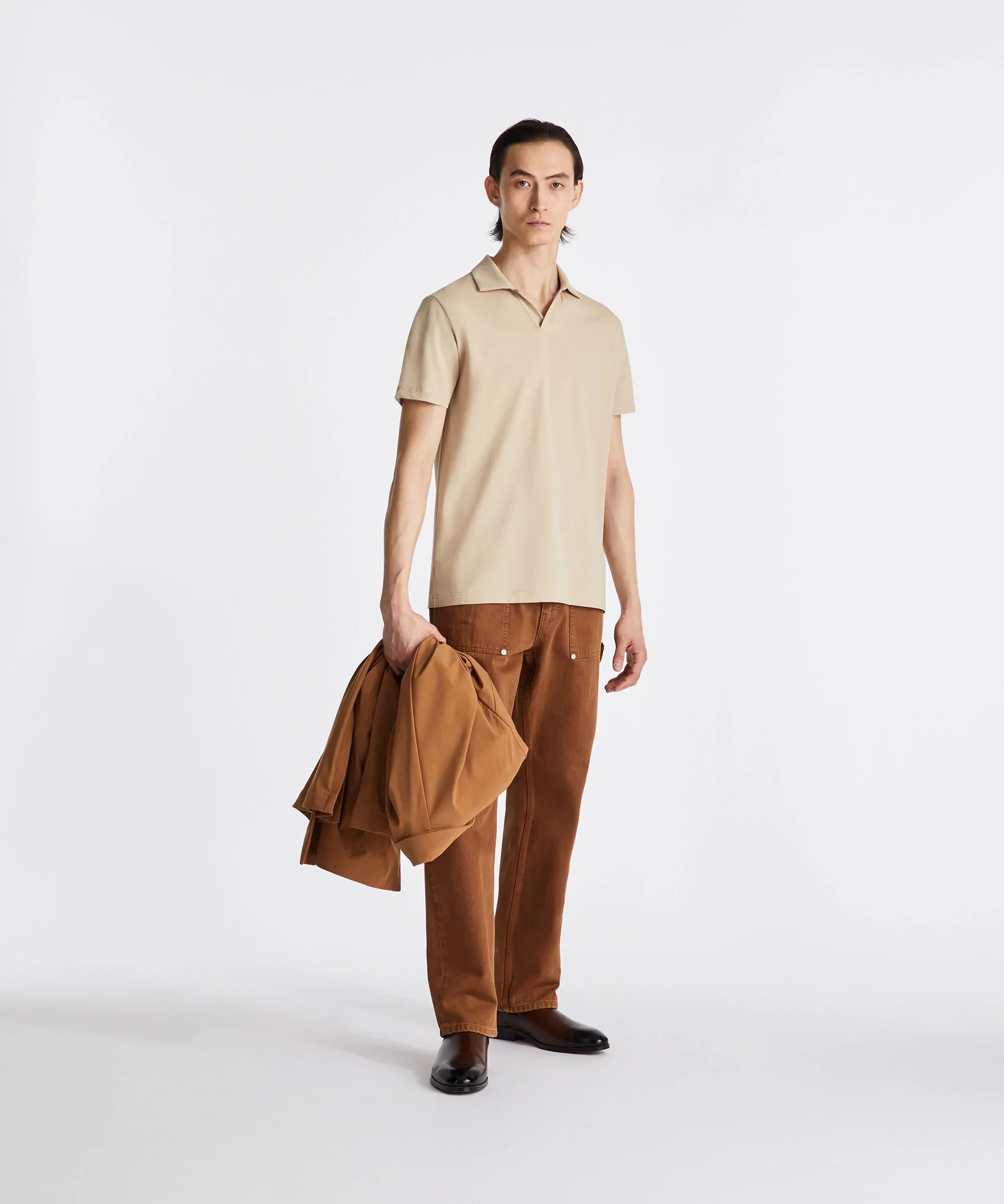Modello uomo indossa polo beige e pantaloni marroni, look casual elegante sartoriale.