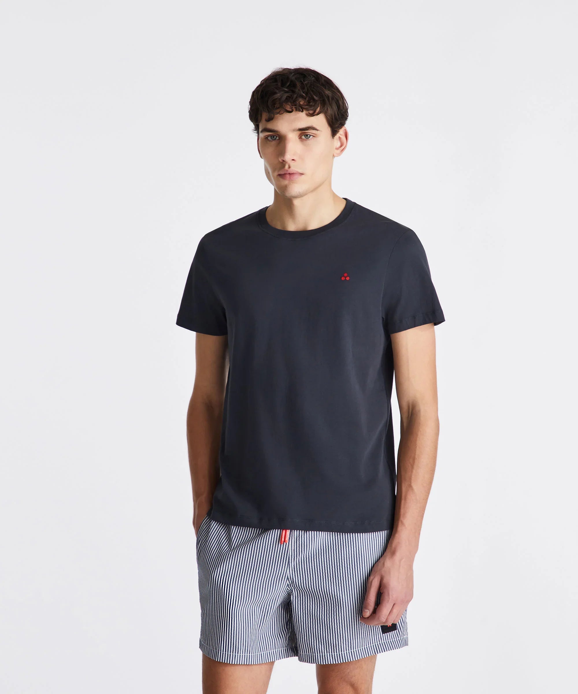 Modello indossa t-shirt nera e pantaloncini a righe, abbigliamento uomo casual estivo