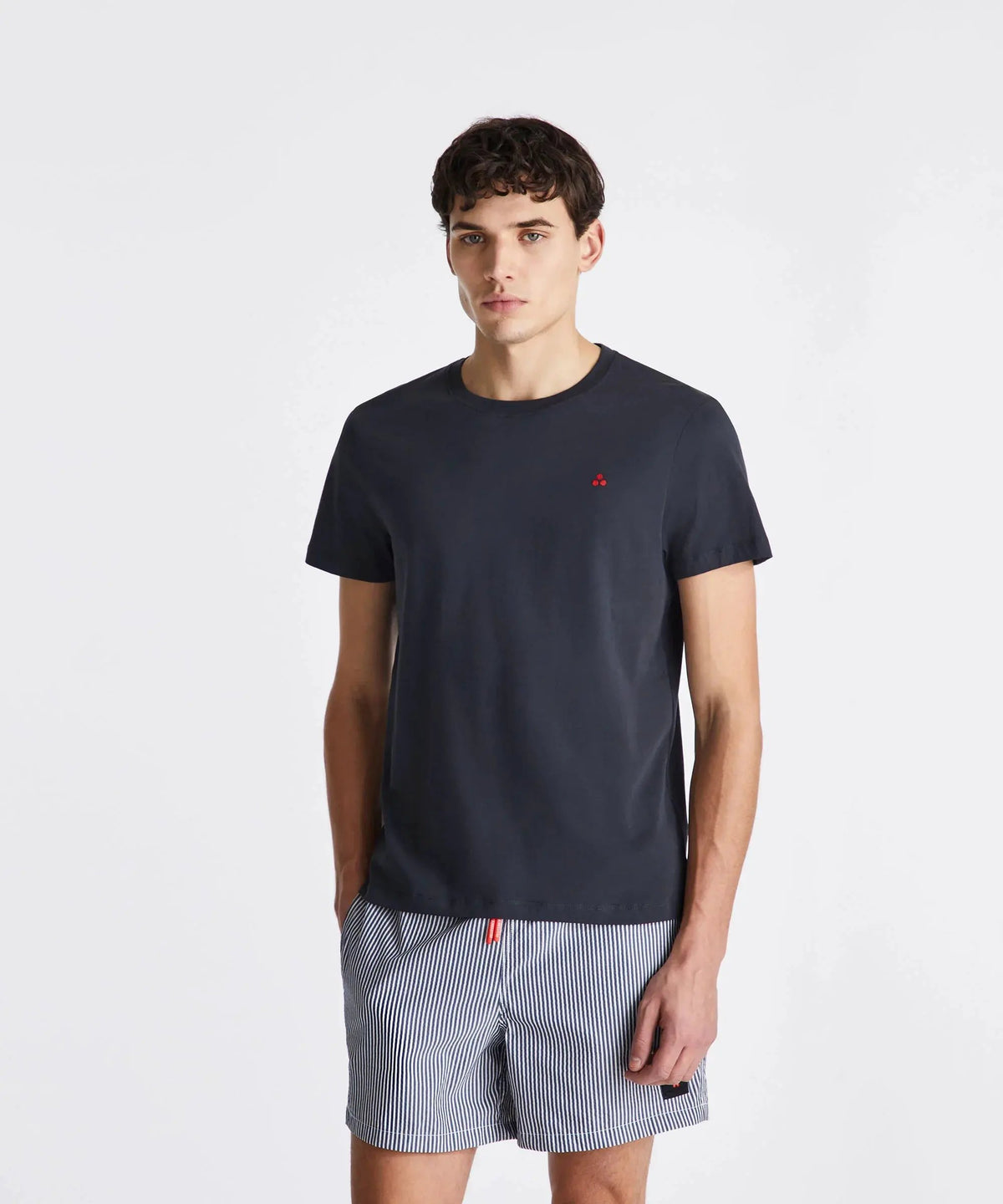 Modello indossa t-shirt nera e pantaloncini a righe, abbigliamento uomo casual estivo