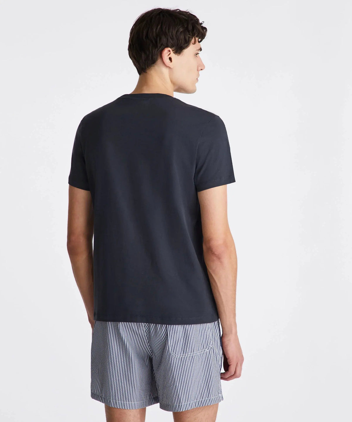 Uomo di spalle con t-shirt nera e pantaloncini corti a righe, moda estiva uomo