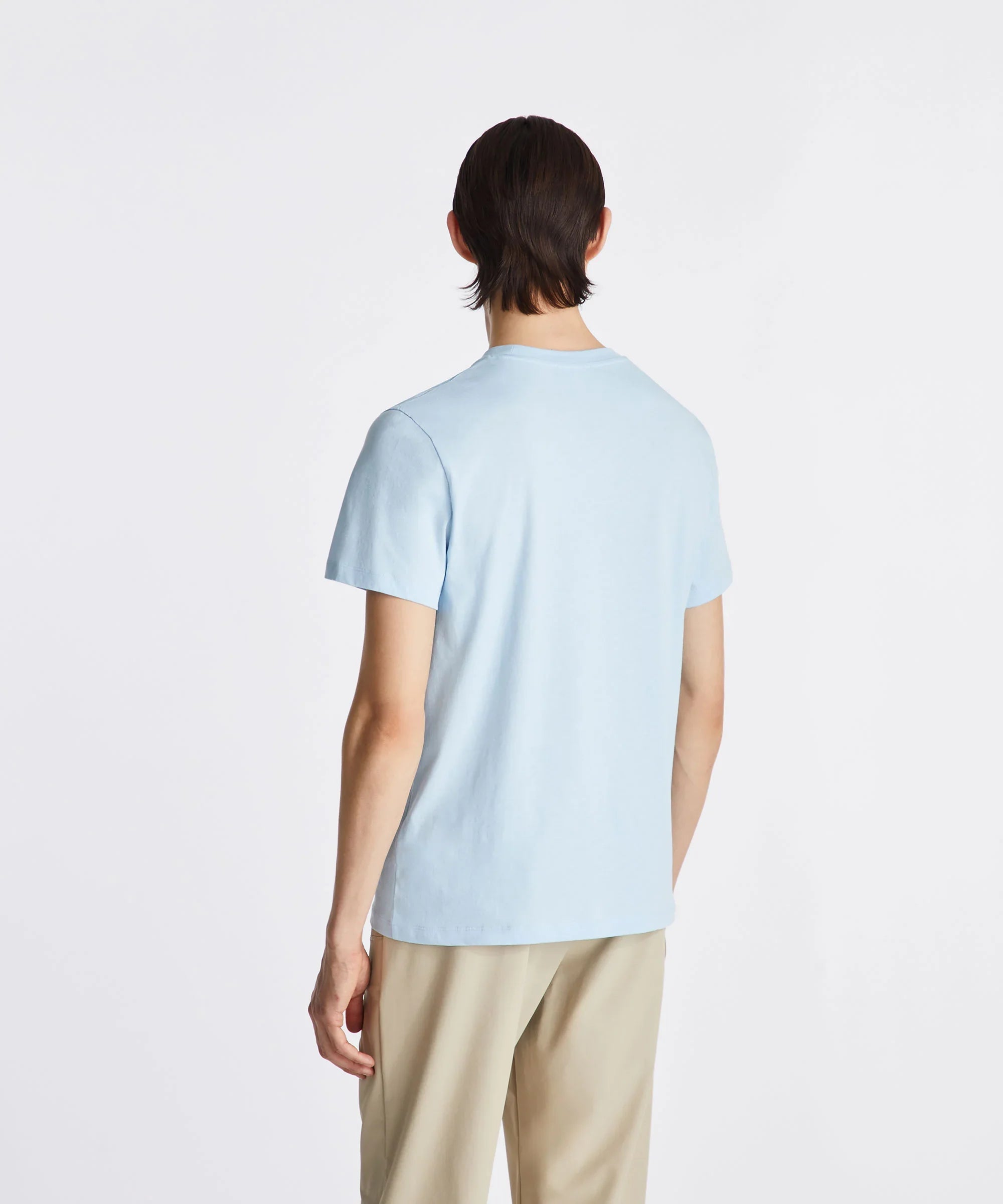 Modello di schiena con t-shirt celeste e pantaloni beige uomo, sfondo bianco