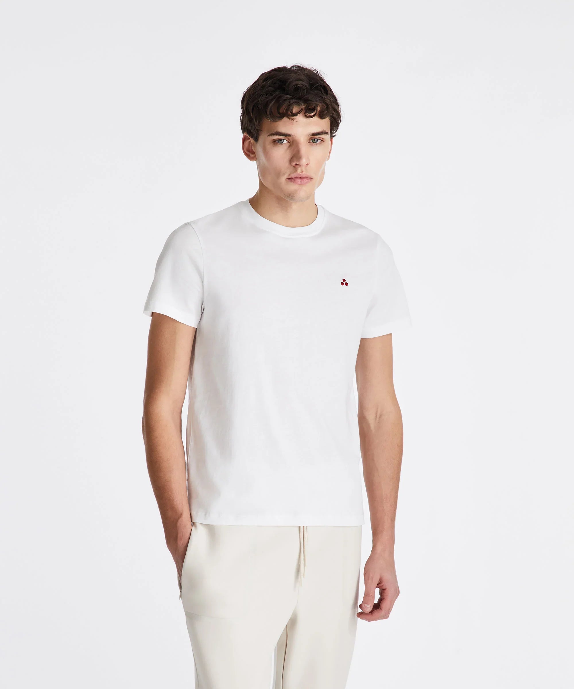 Modello indossa t-shirt bianca da uomo con piccolo logo rosso, outfit casual elegante.