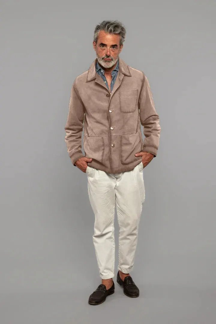 Uomo maturo con giacca beige scamosciata, camicia denim e pantaloni bianchi elegante.