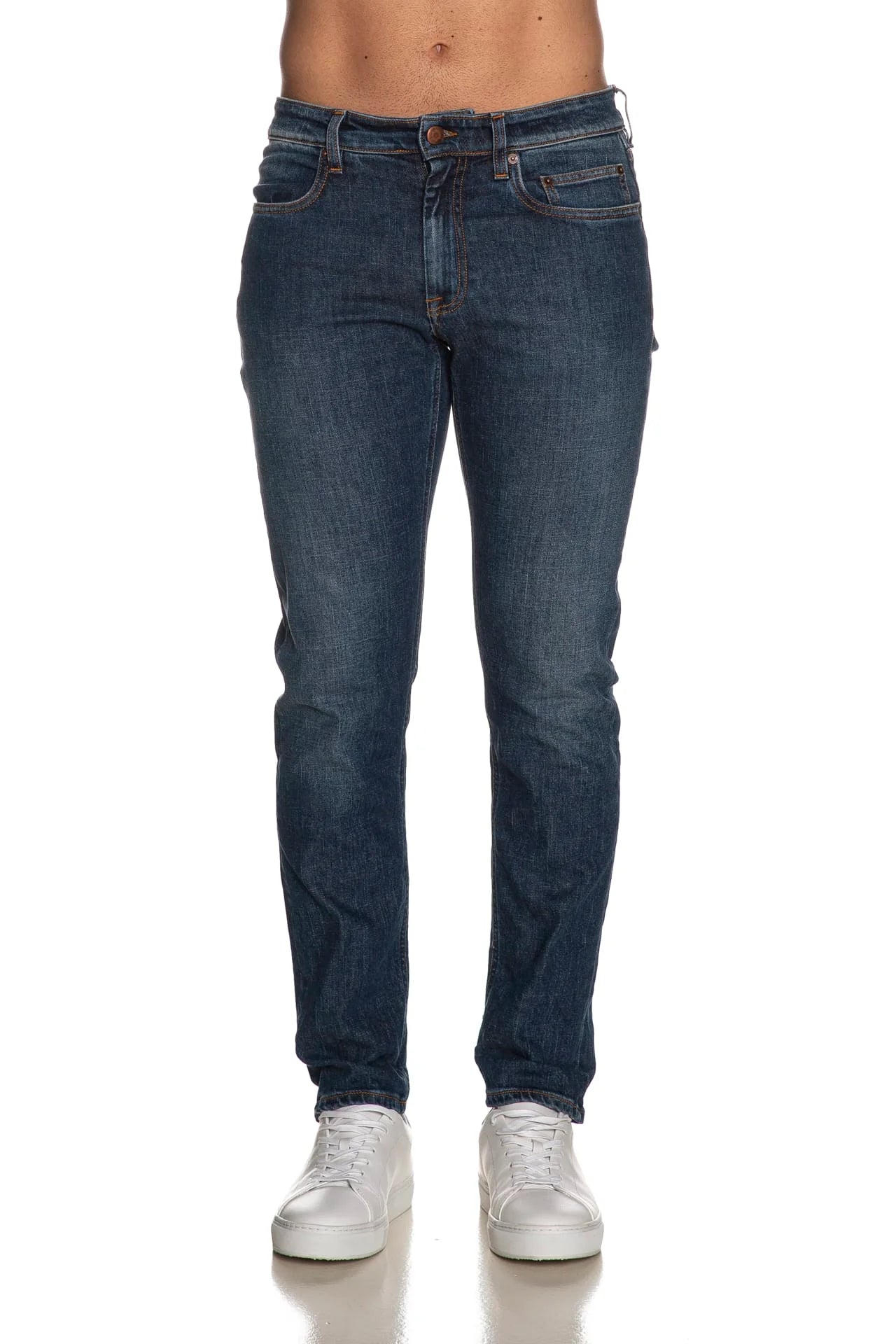 Jeans slim fit uomo in denim blu scuro, cinque tasche, indossati con sneakers bianche.