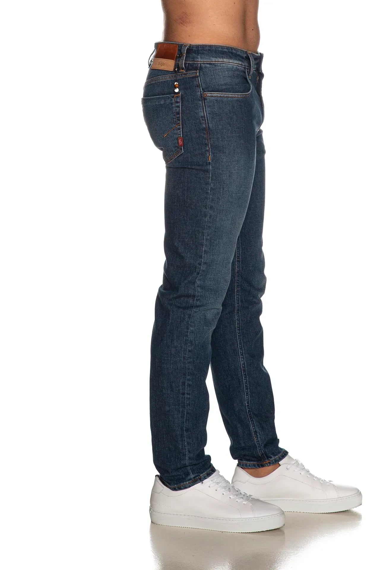 Jeans uomo slim fit blu scuro indossati, tasca laterale e sneakers bianche visibili