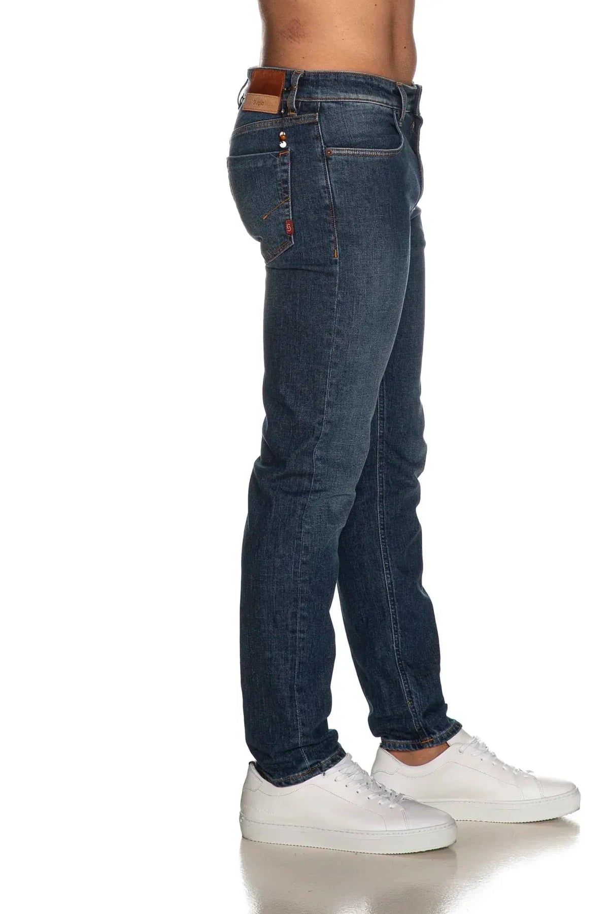 Jeans uomo slim fit blu scuro indossati, tasca laterale e sneakers bianche visibili