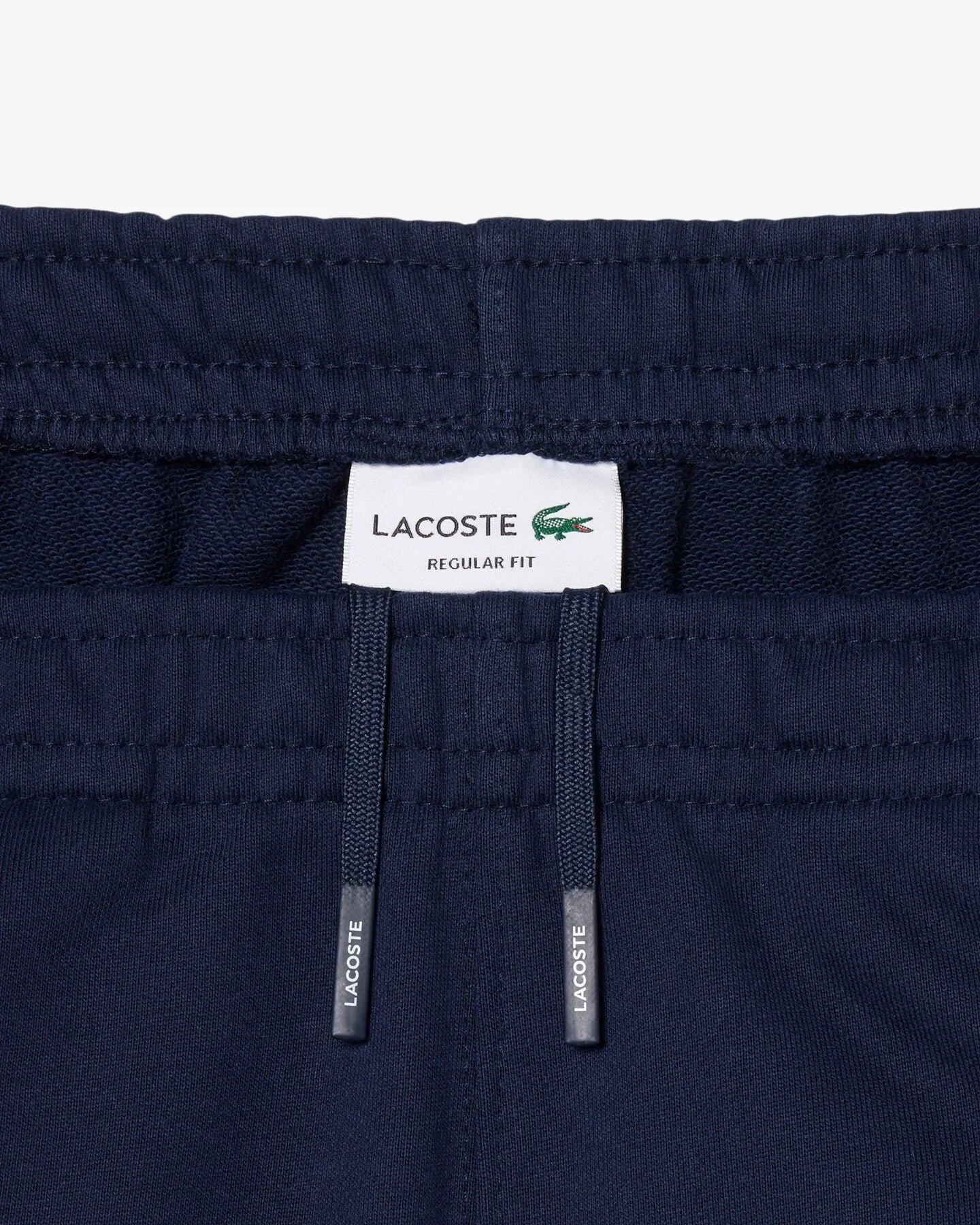 Dettaglio vita pantaloni blu uomo con coulisse e etichetta Lacoste, stile casual