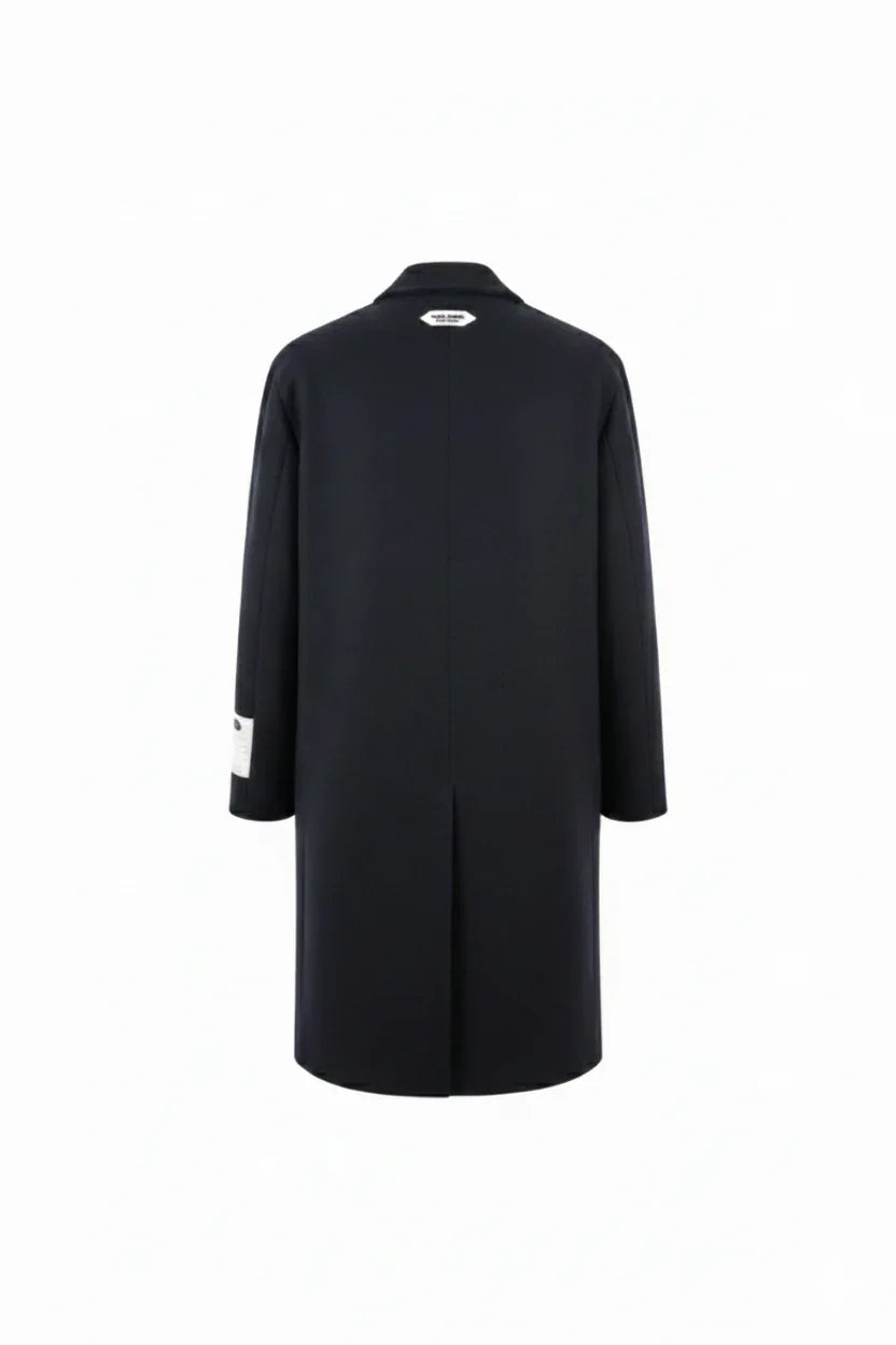 Cappotto lungo uomo nero elegante visto da dietro, dettaglio etichetta sul colletto.