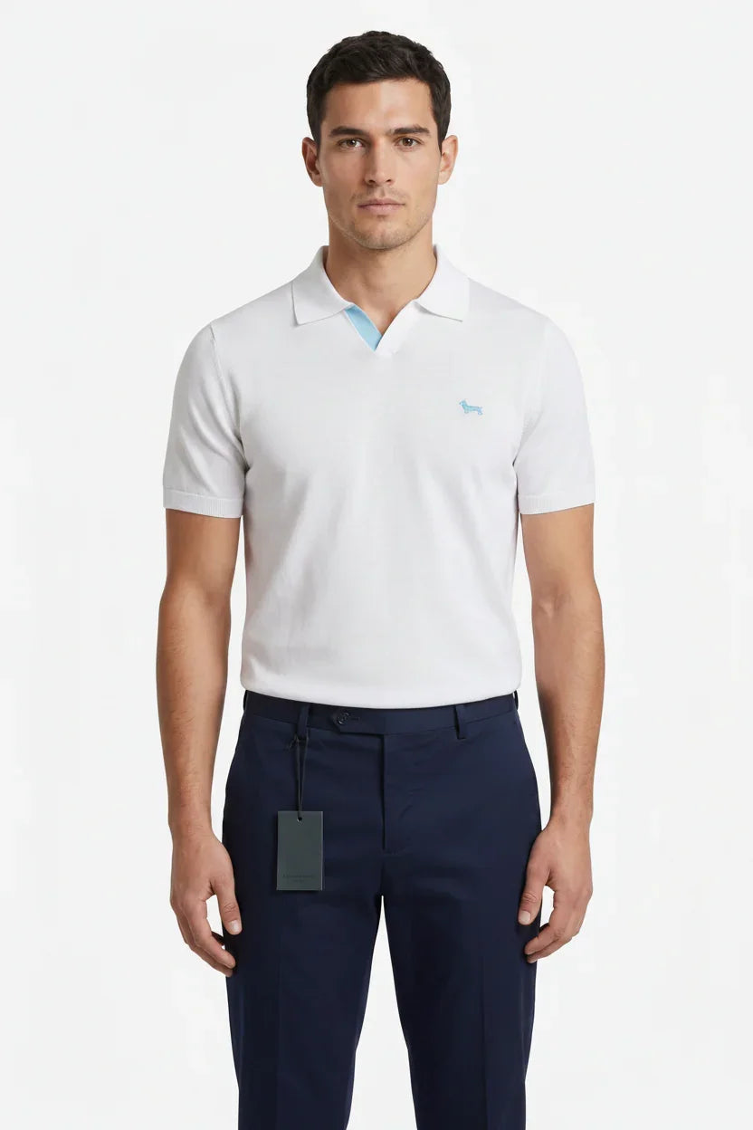 Modello indossa polo bianca da uomo con logo azzurro e pantaloni blu eleganti