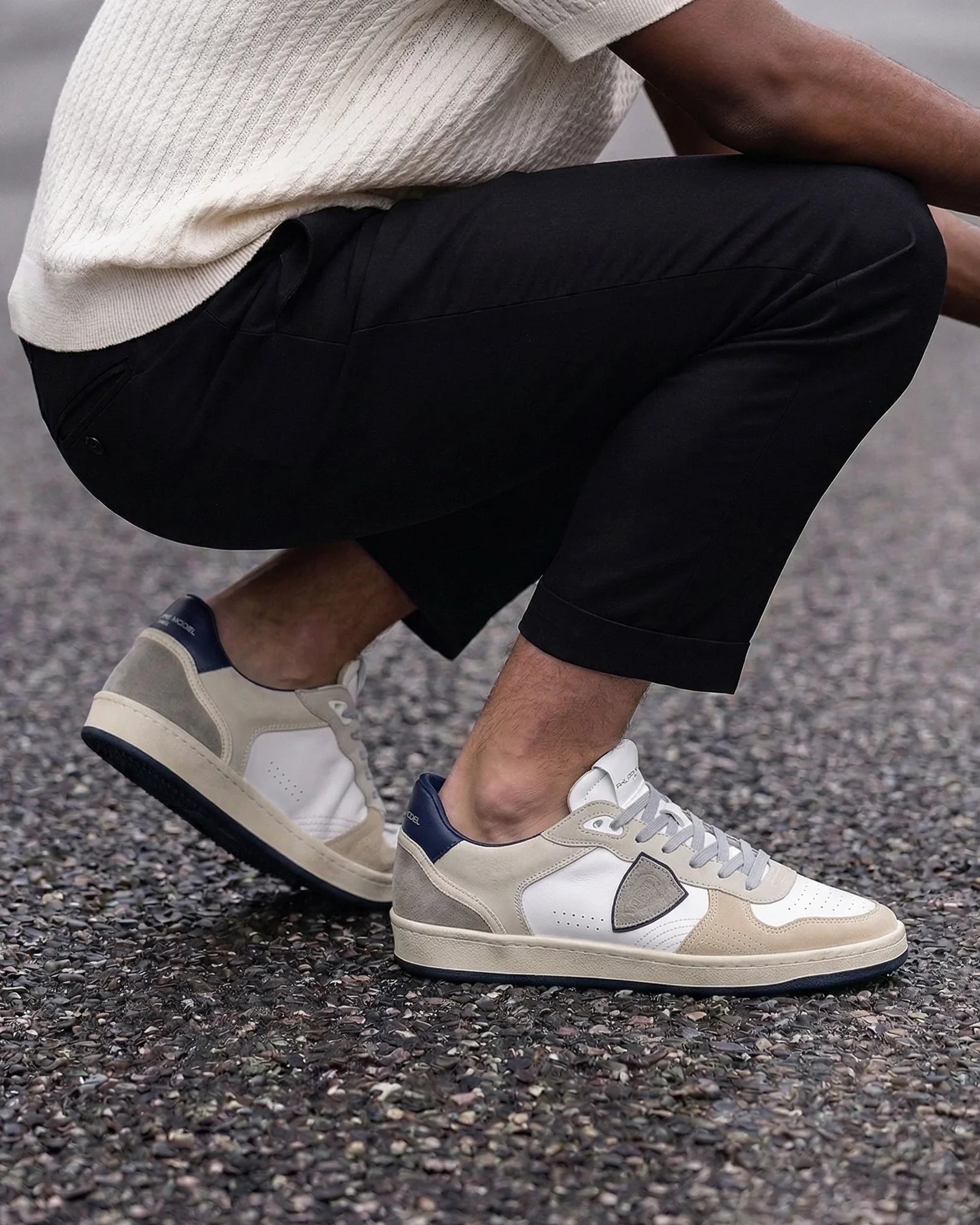 Sneakers uomo bianche e beige in pelle e camoscio, stile casual, indossate con pantaloni neri