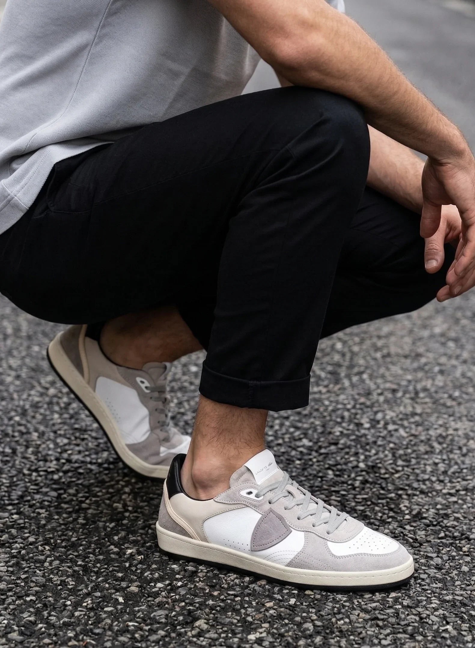 Sneakers uomo in pelle e suede beige e bianco, stile casual, su asfalto, pantaloni neri