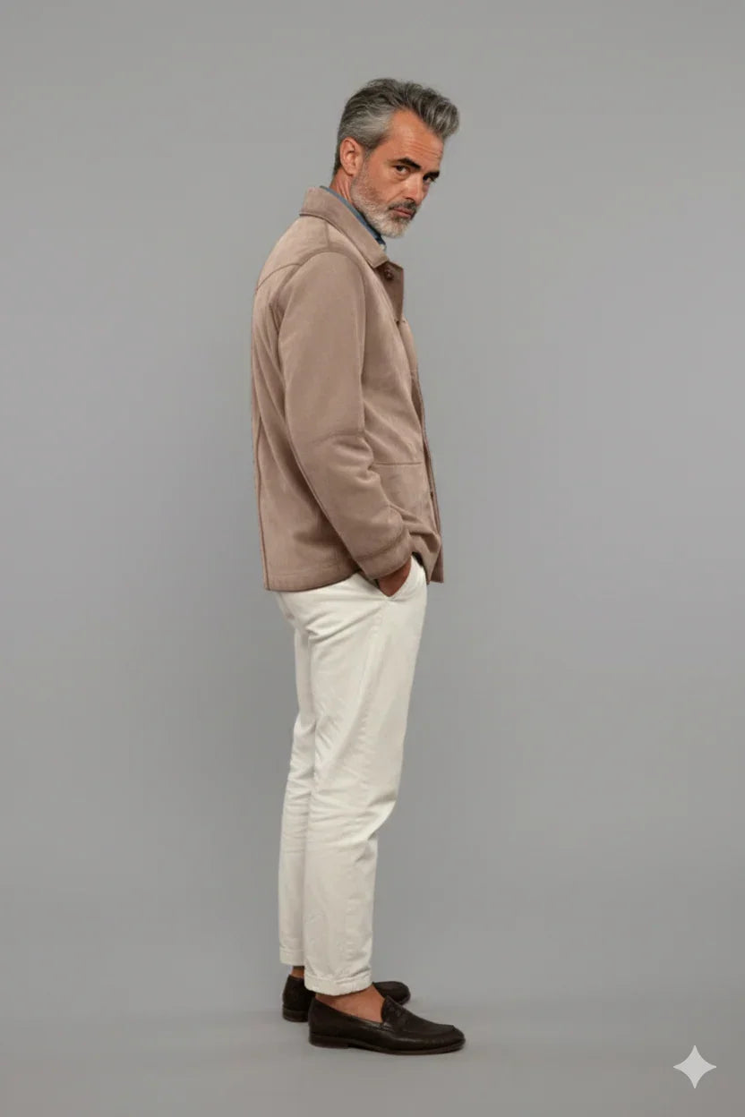 Uomo elegante con giacca beige, pantaloni bianchi e mocassini marroni su sfondo neutro