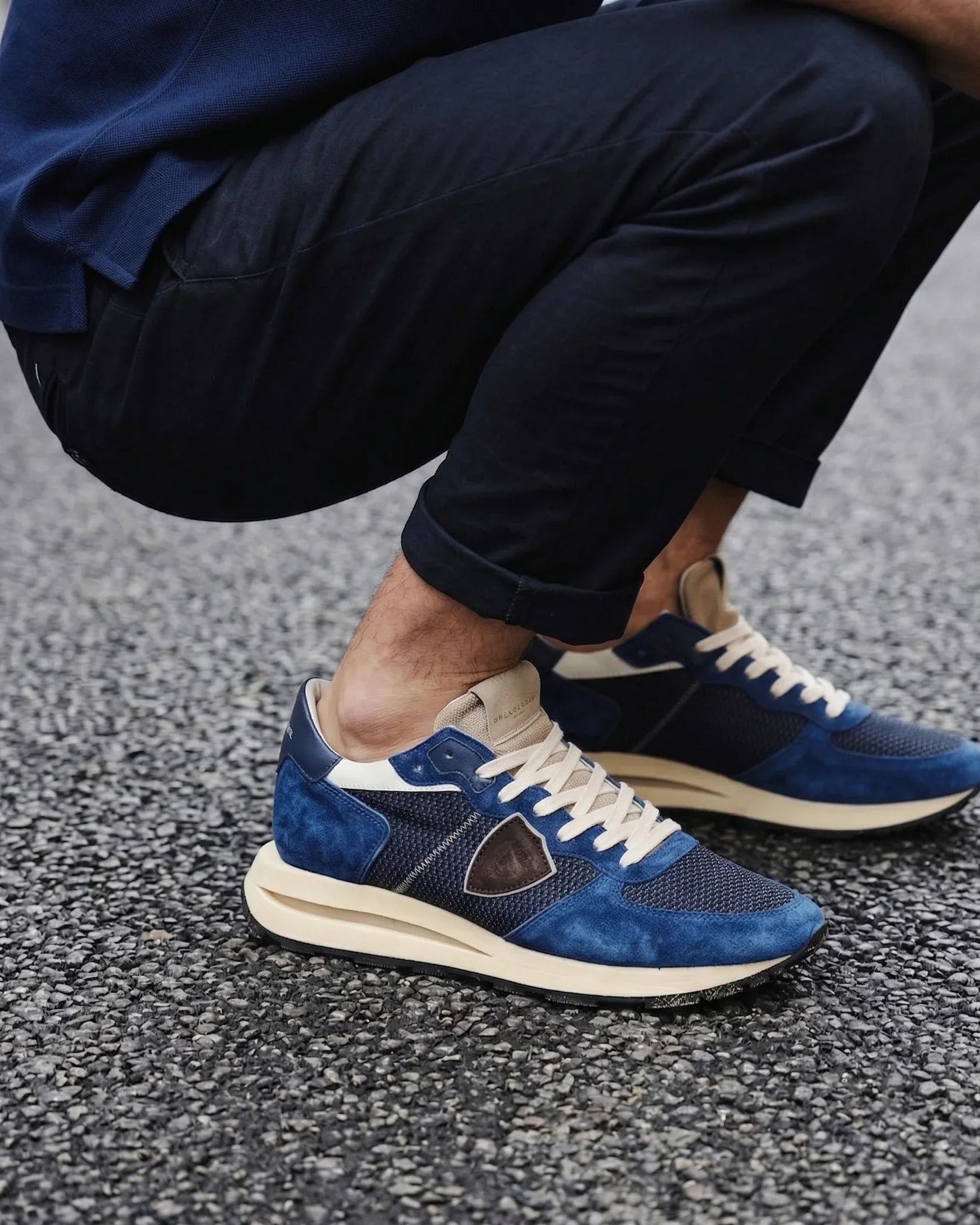 Sneakers uomo blu scuro in pelle e tessuto, stile casual, indossate su strada asfaltata