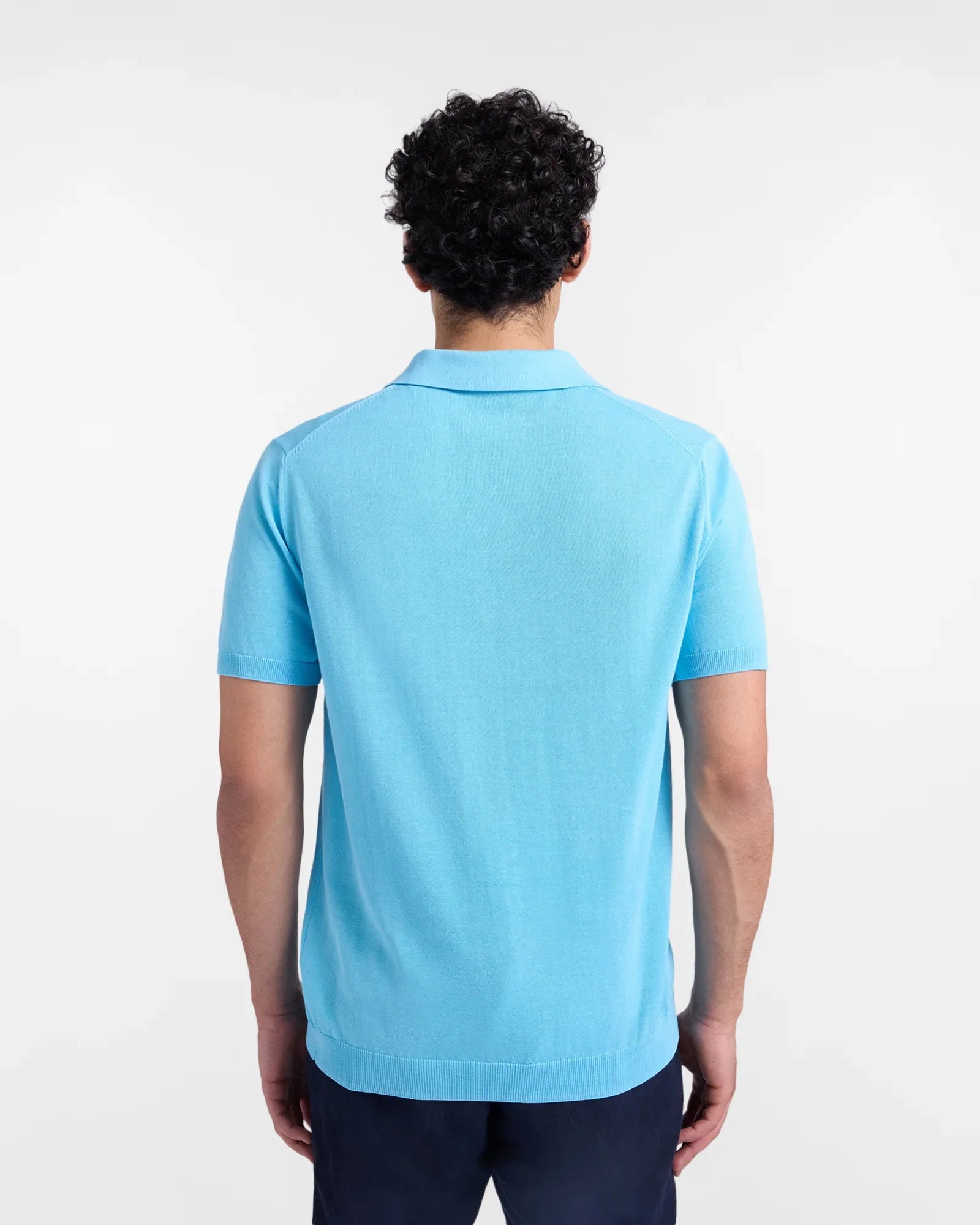 Uomo di schiena con polo azzurra a maniche corte e pantaloni blu, moda abbigliamento uomo