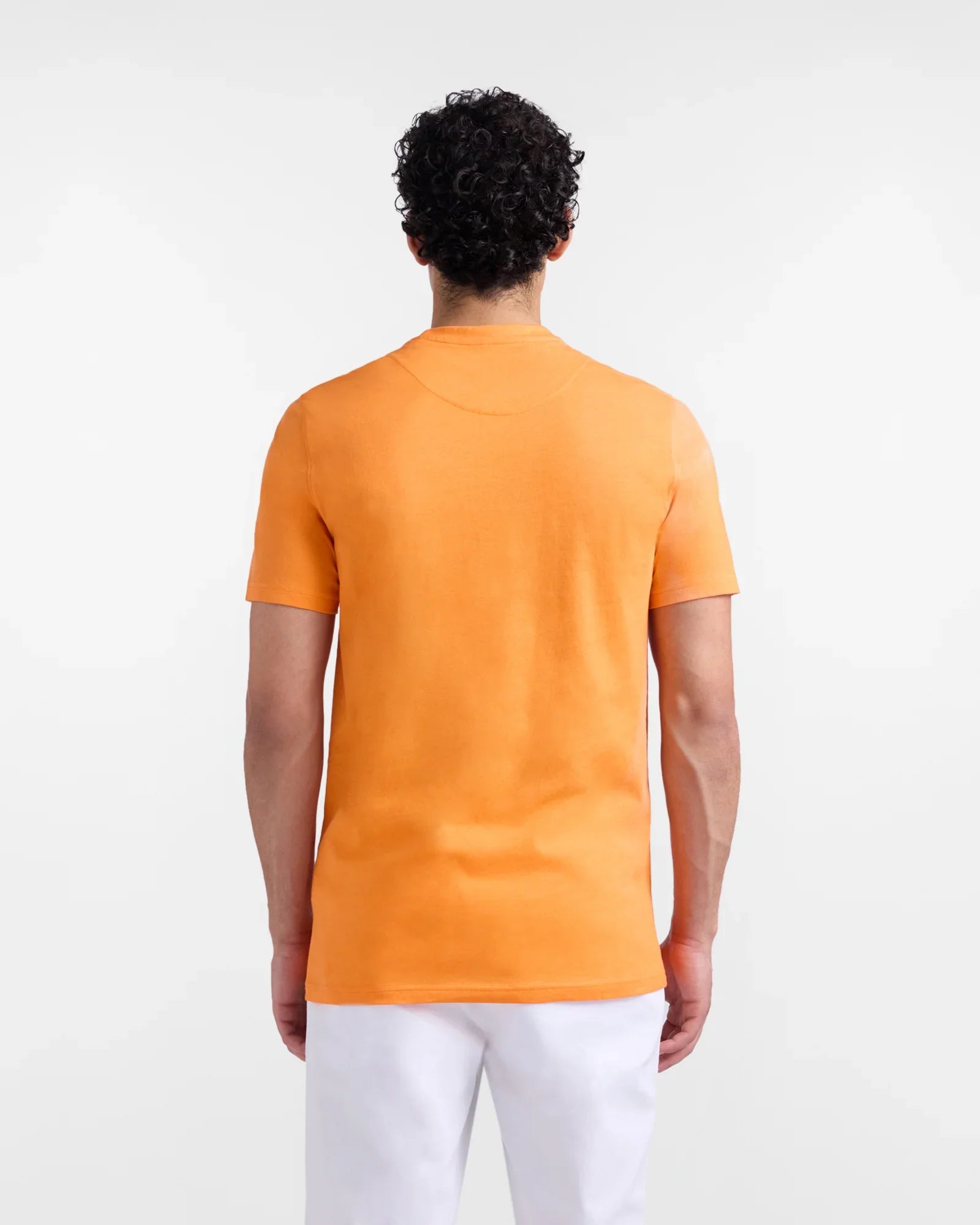 Uomo di spalle con t-shirt arancione a maniche corte e pantaloni bianchi, moda uomo