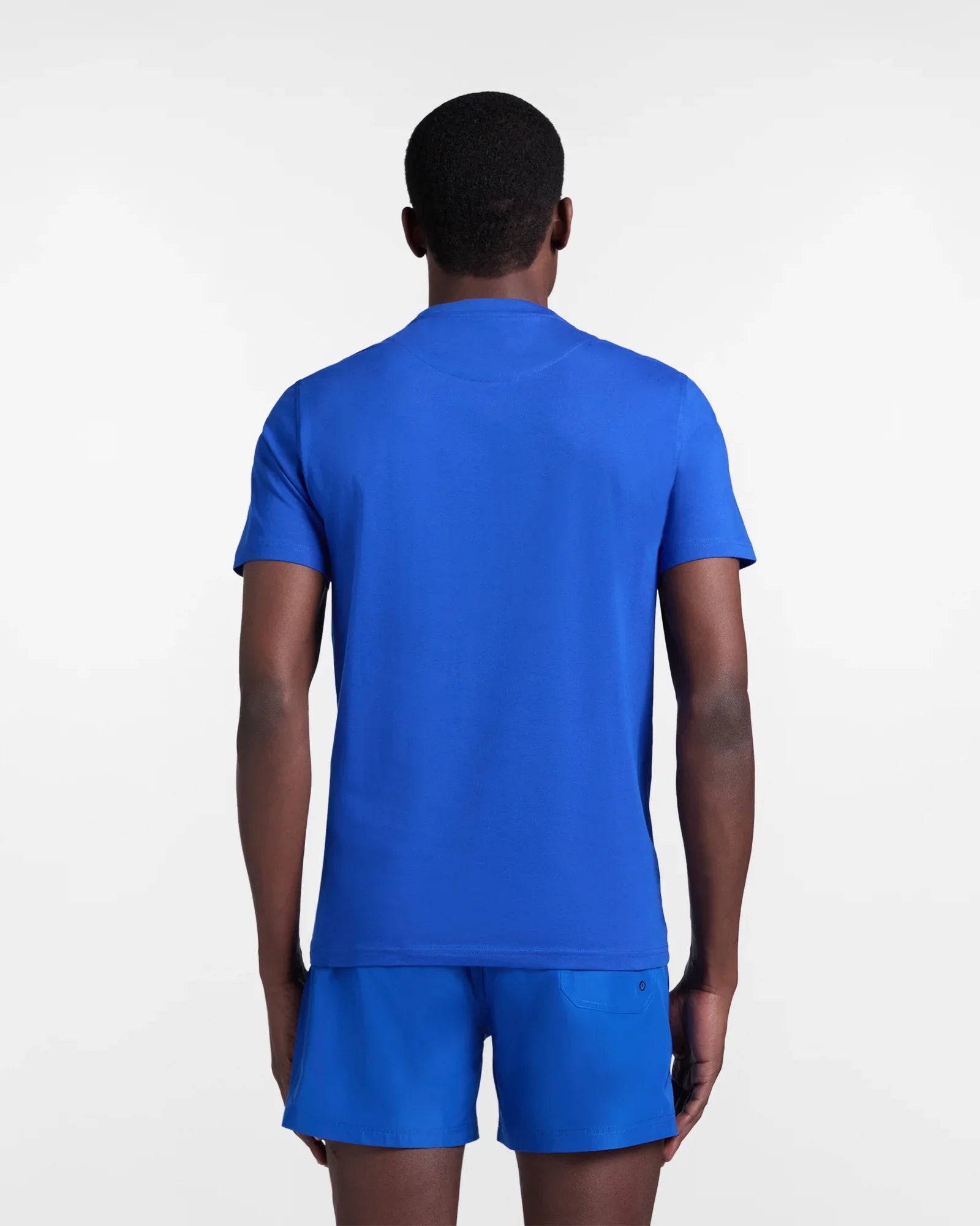 Uomo di spalle con t-shirt e pantaloncini corti blu, abbigliamento casual estivo