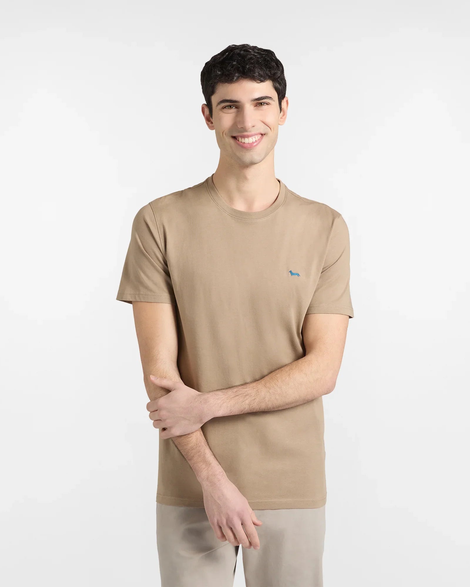 Modello indossa t-shirt beige da uomo con piccolo logo ricamato, stile casual elegante.