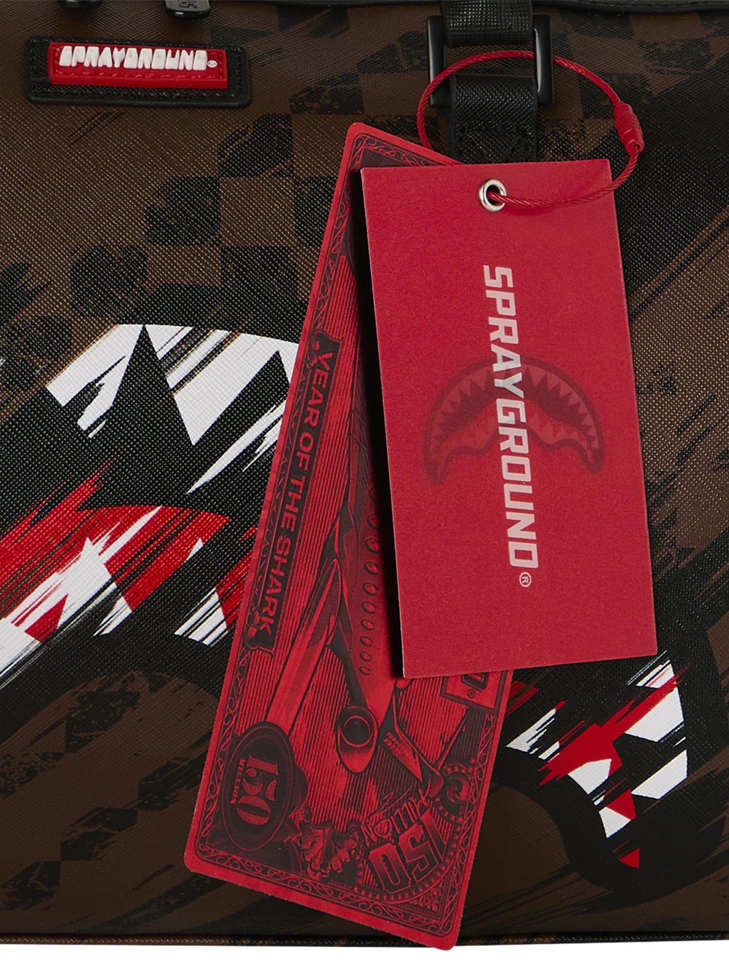 Dettaglio zaino Sprayground marrone con etichette rosse, design effetto graffiti