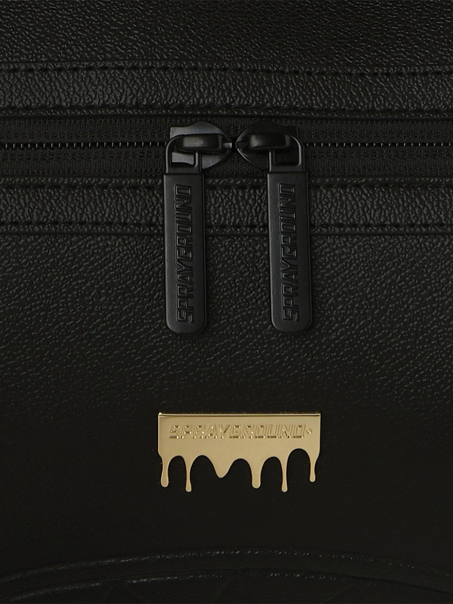 Dettaglio di una borsa nera con zip e logo Sprayground dorato, accessorio moda elegante.