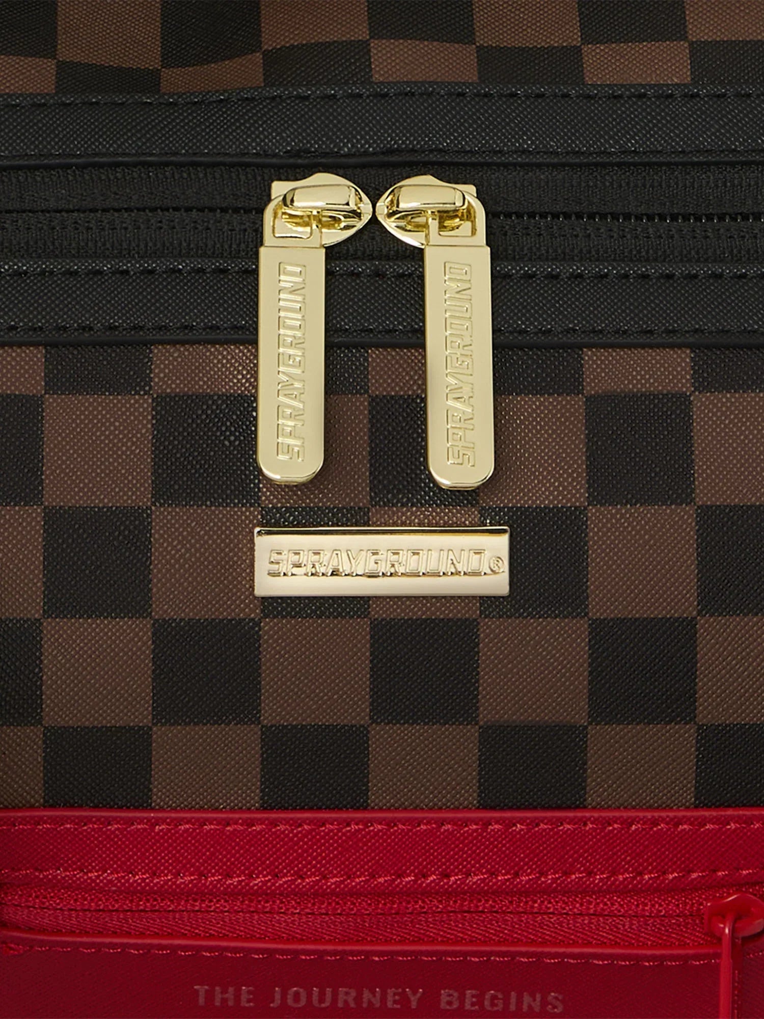 Dettaglio zaino a quadretti marrone con finiture oro e base rossa, zip e logo Sprayground.