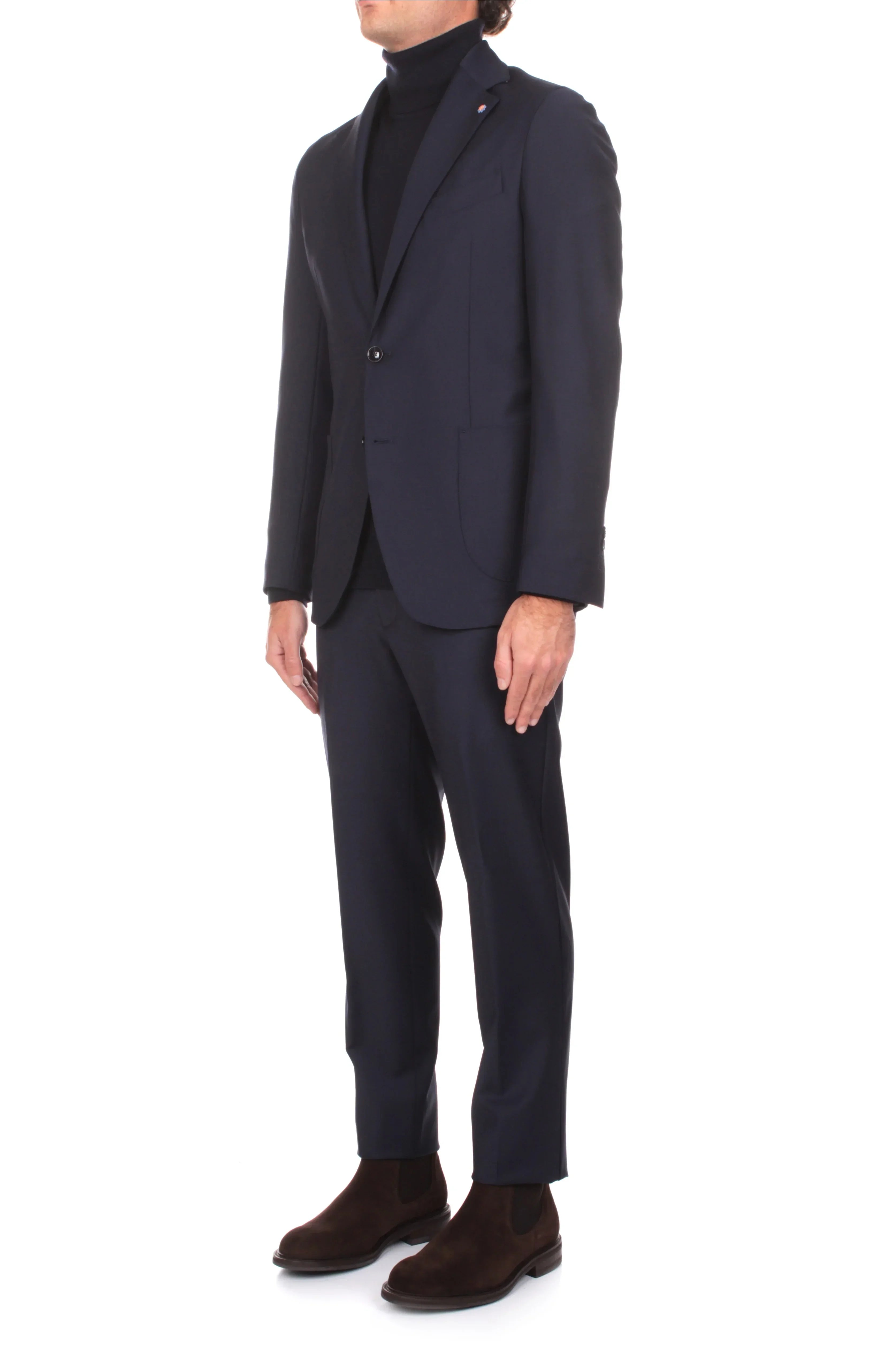 Completo uomo blu elegante, giacca e pantalone, dolcevita nero e stivaletti marroni.