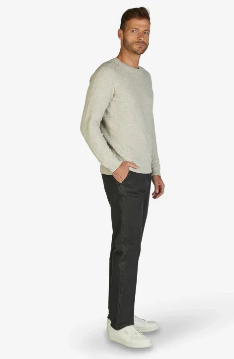 Modello uomo con maglione grigio chiaro, pantaloni neri e sneakers bianche, stile casual
