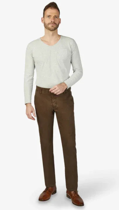 Modello indossa pantaloni marroni da uomo, camicia chiara e scarpe eleganti cuoio.