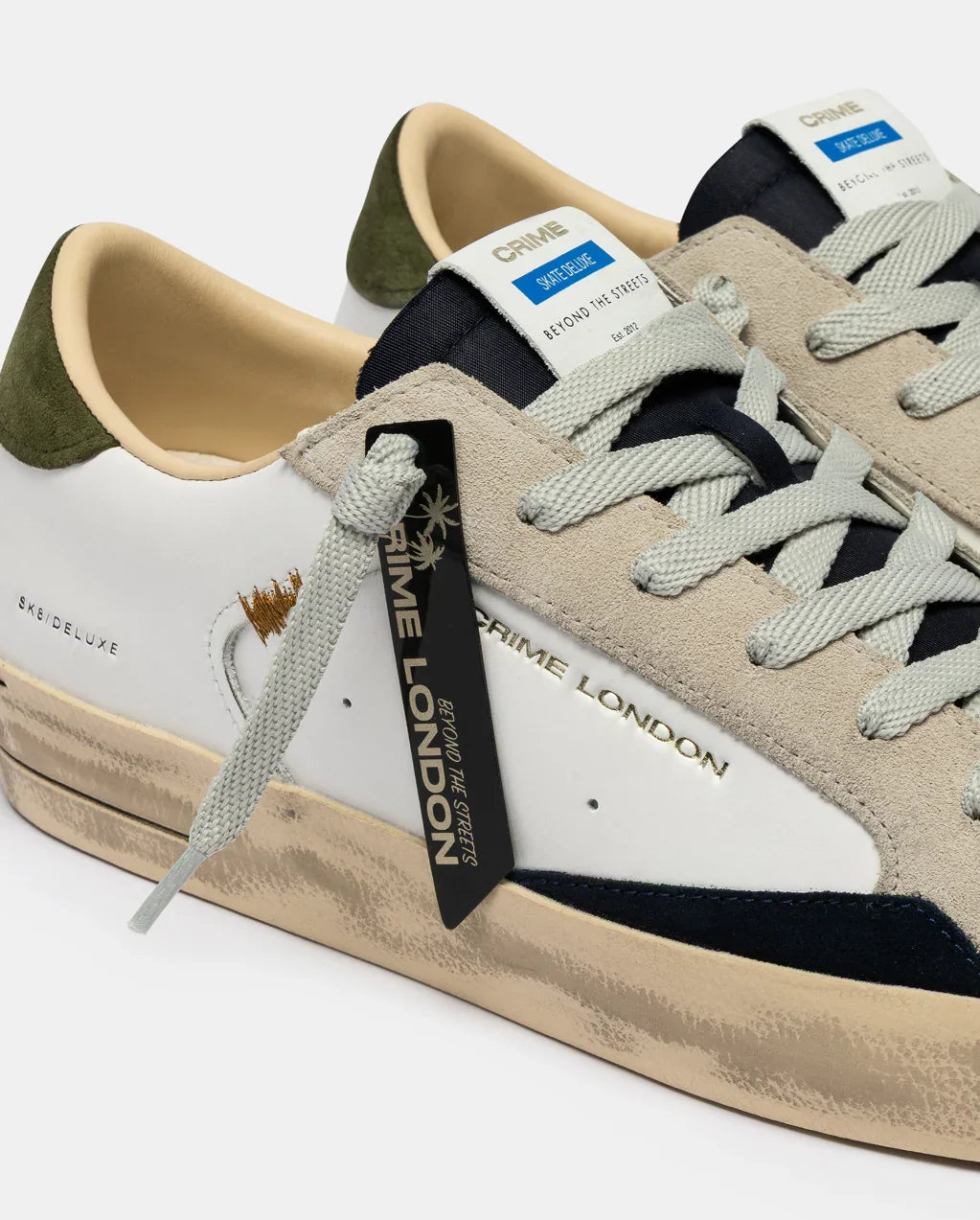 Sneakers Crime London uomo in pelle bianca con dettagli suede beige e tallone verde, stile casual.