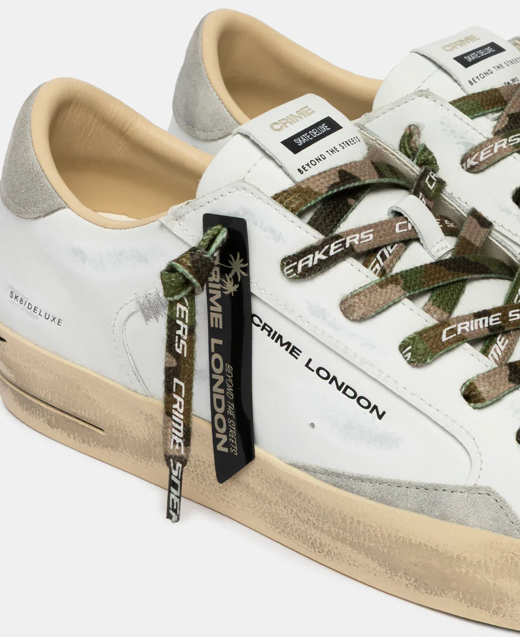Sneakers uomo bianche con dettagli camouflage, suola beige, logo Crime London visibile.