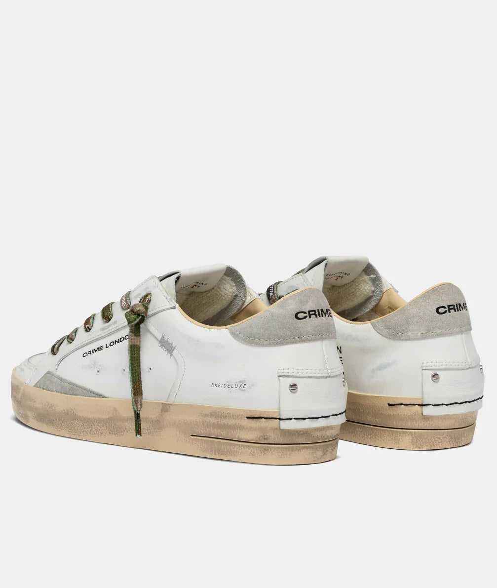 Sneakers uomo bianche effetto vintage con dettagli grigi, lacci camouflage e suola usurata.