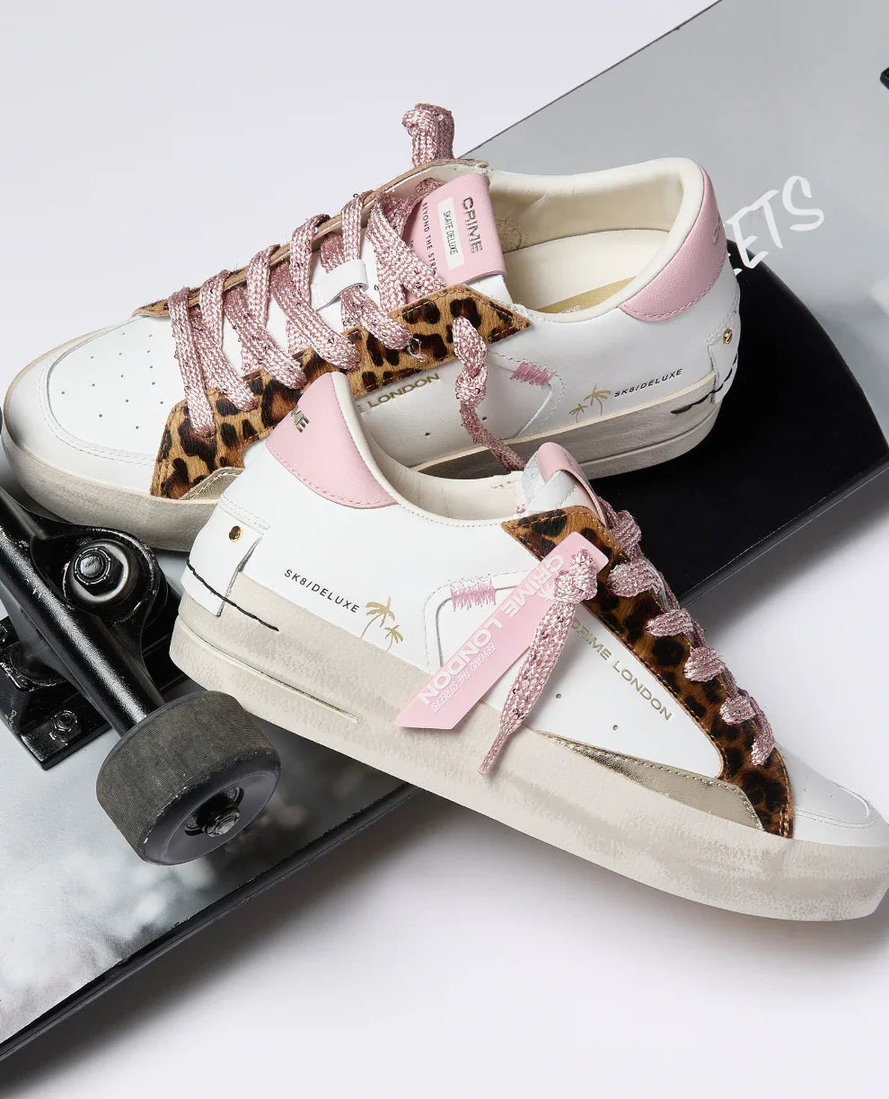 Sneakers bianche da donna con dettagli rosa e animalier, su skateboard, moda streetwear