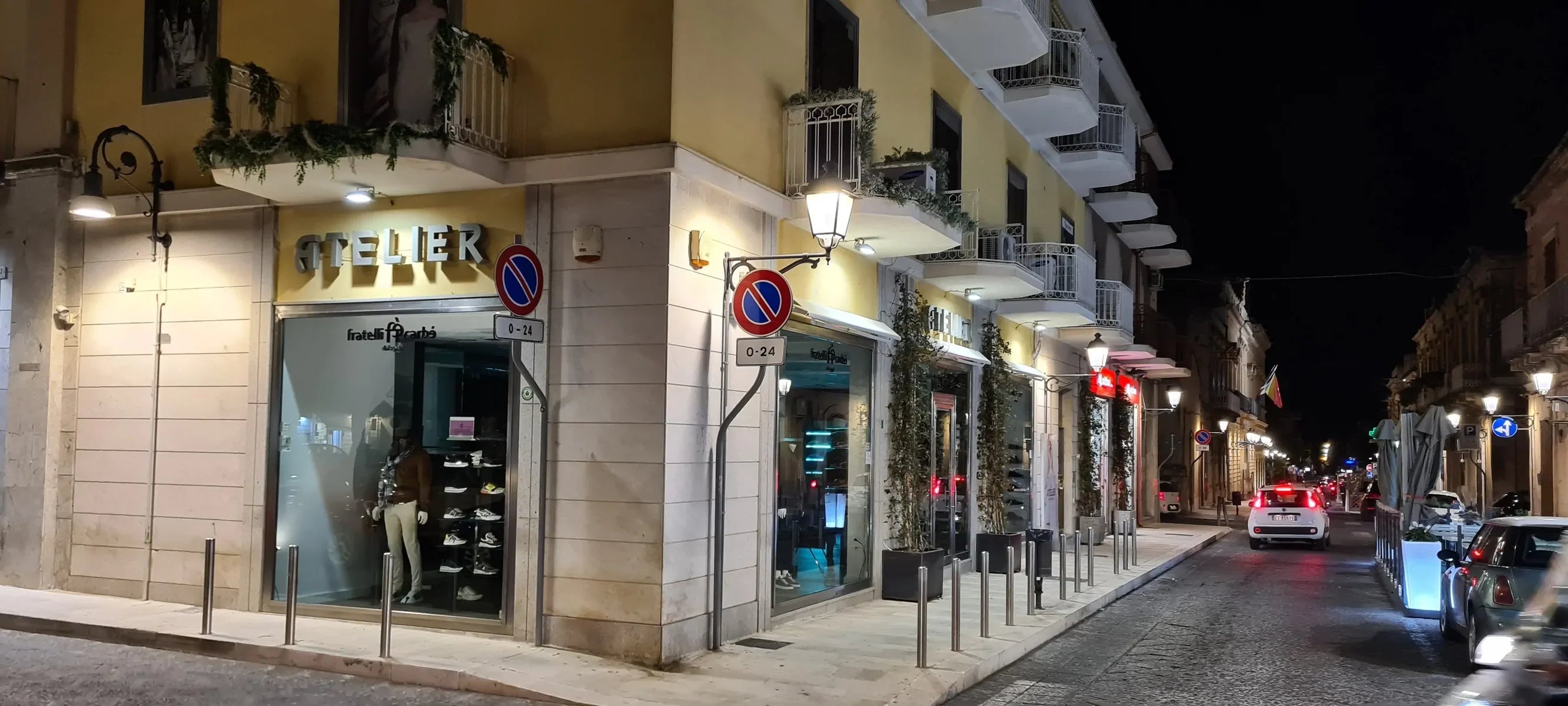 Vetrina atelier abbigliamento e calzature uomo donna in centro città di notte