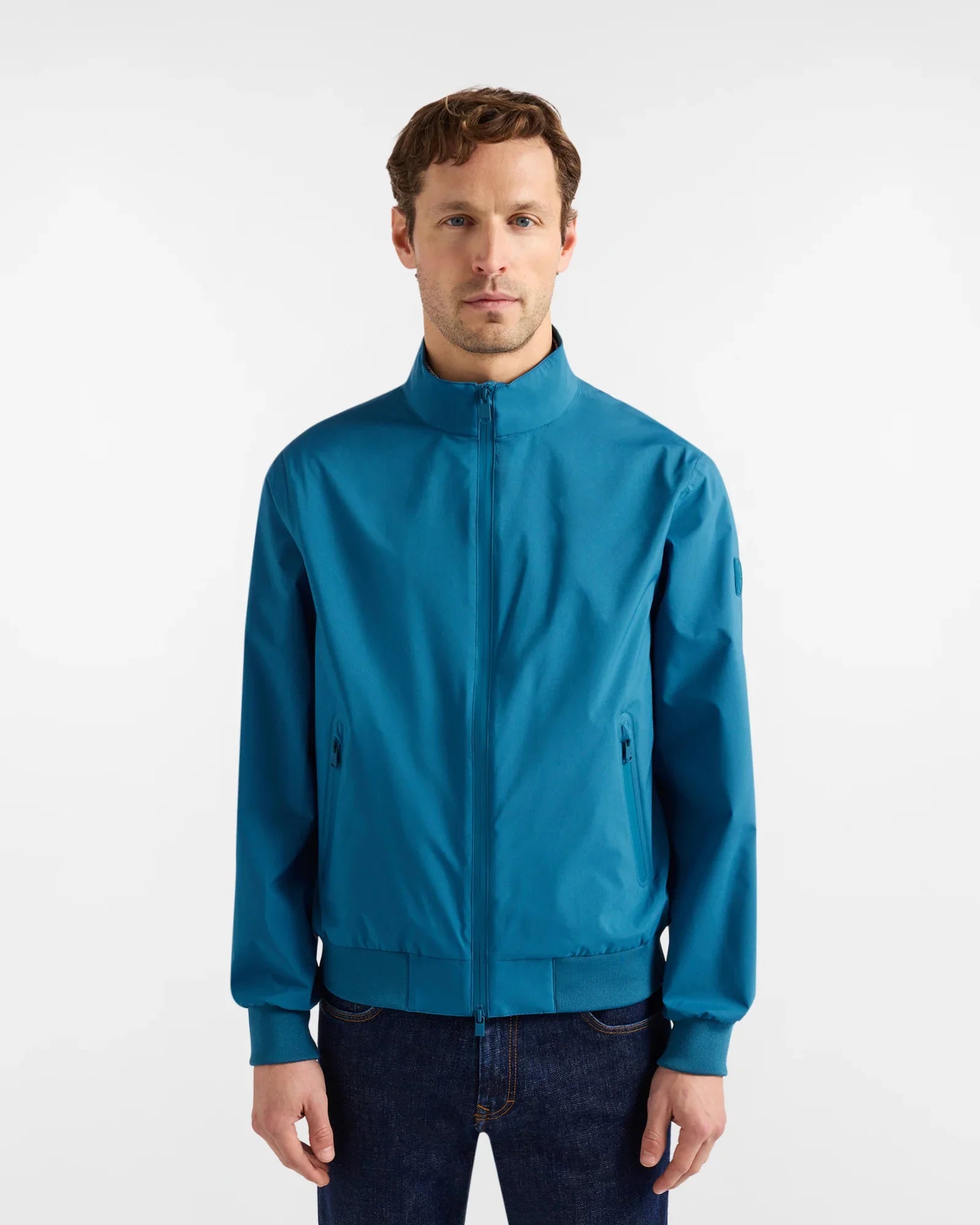 Giacca uomo blu scuro con zip, collo alto e tasche laterali, abbigliamento casual elegante.