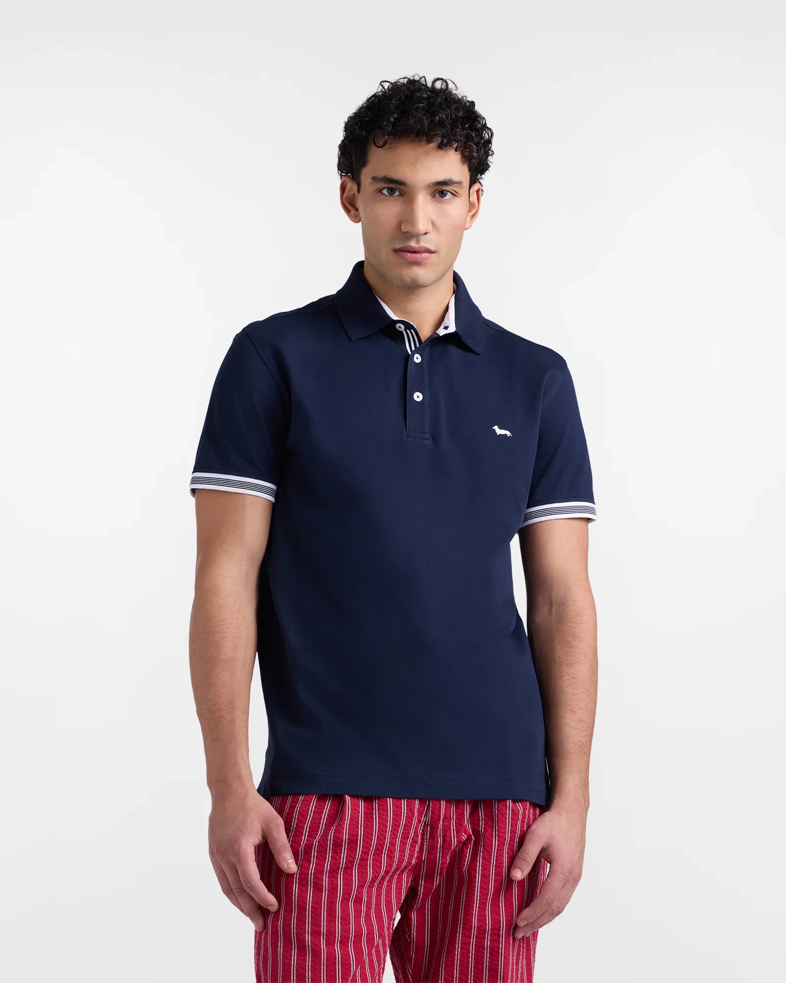 Polo uomo blu navy a manica corta con dettagli bianchi, pantaloni rossi a righe, moda casual