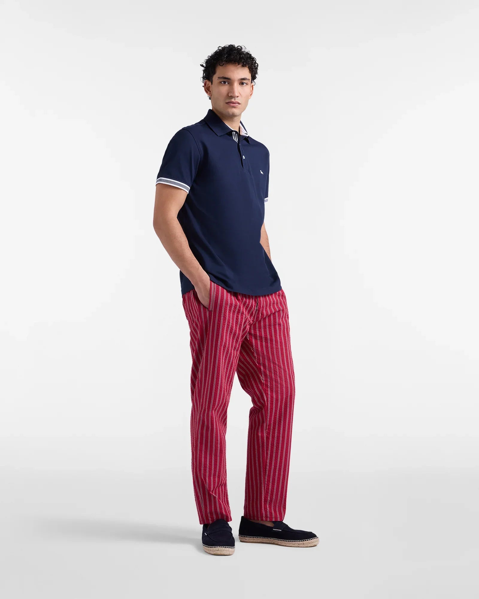 Uomo con polo blu e pantaloni rossi a righe verticali, look casual moda uomo.