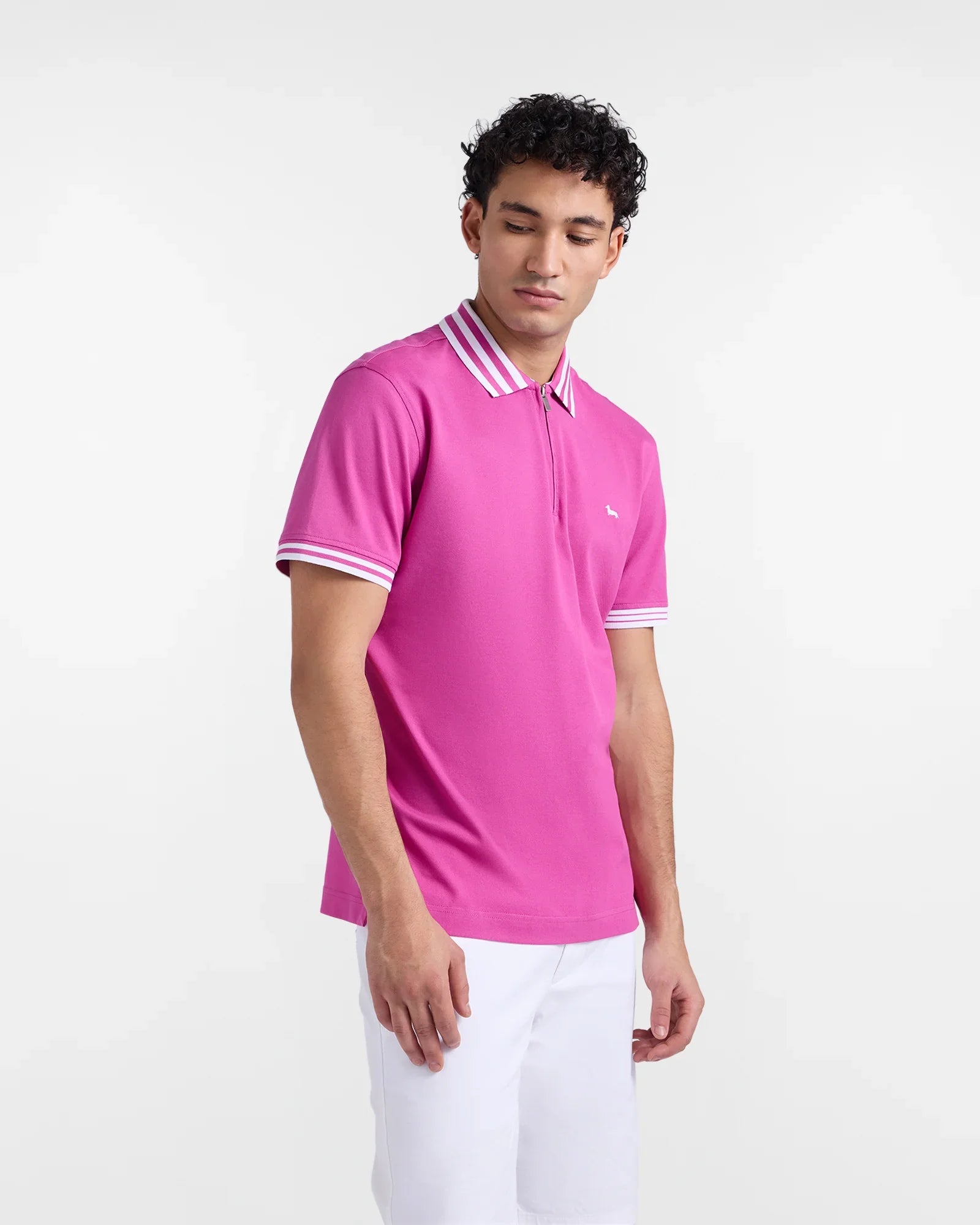 Polo uomo fucsia con zip e colletto a righe bianche, abbinata a pantaloni bianchi.