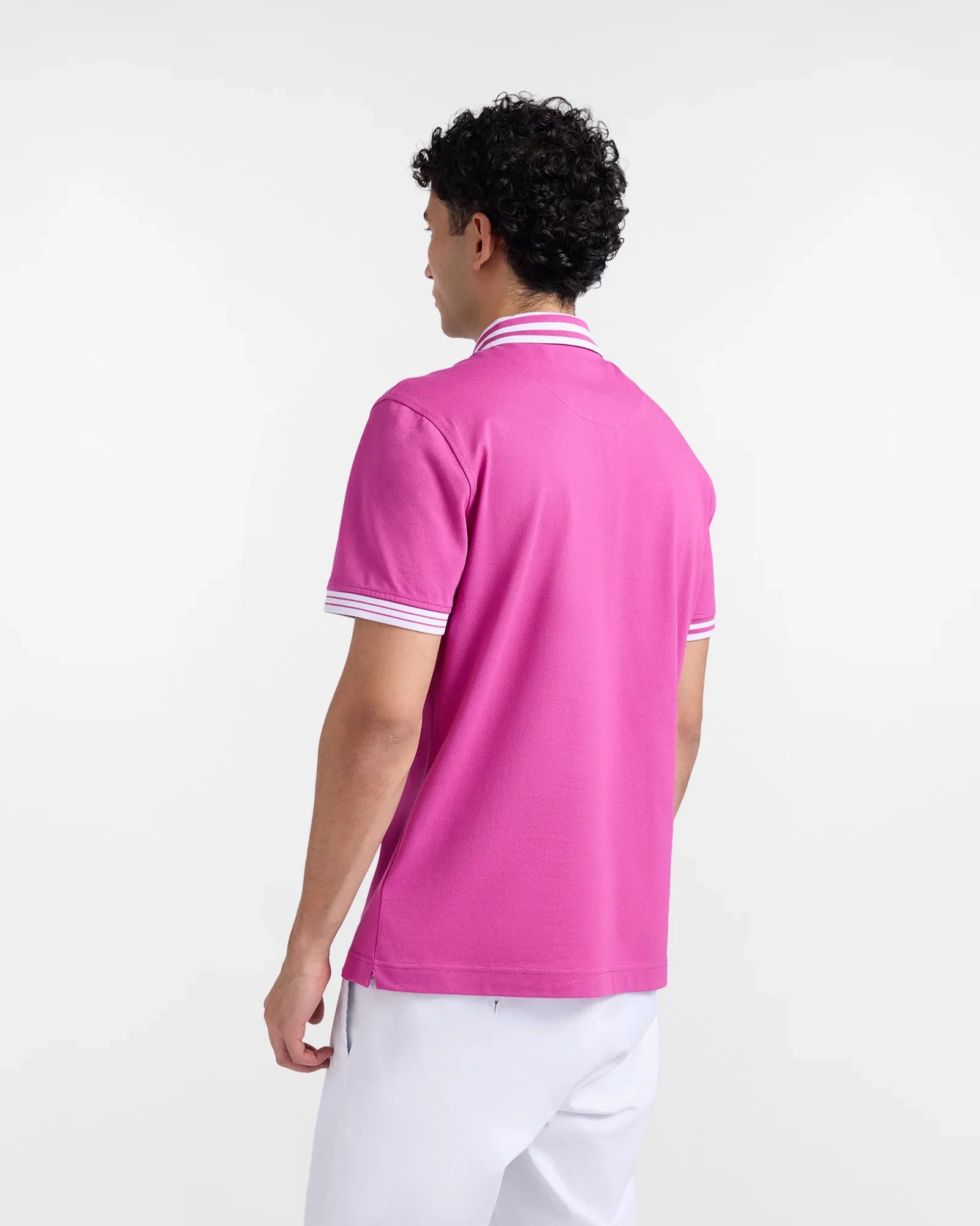 Polo uomo fucsia a maniche corte con colletto e bordi a righe bianche, pantaloni bianchi.