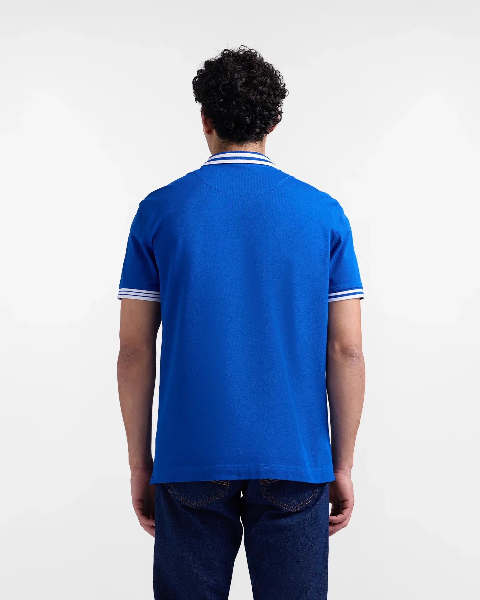 Uomo di spalle con polo blu a maniche corte e dettagli bianchi, stile casual.
