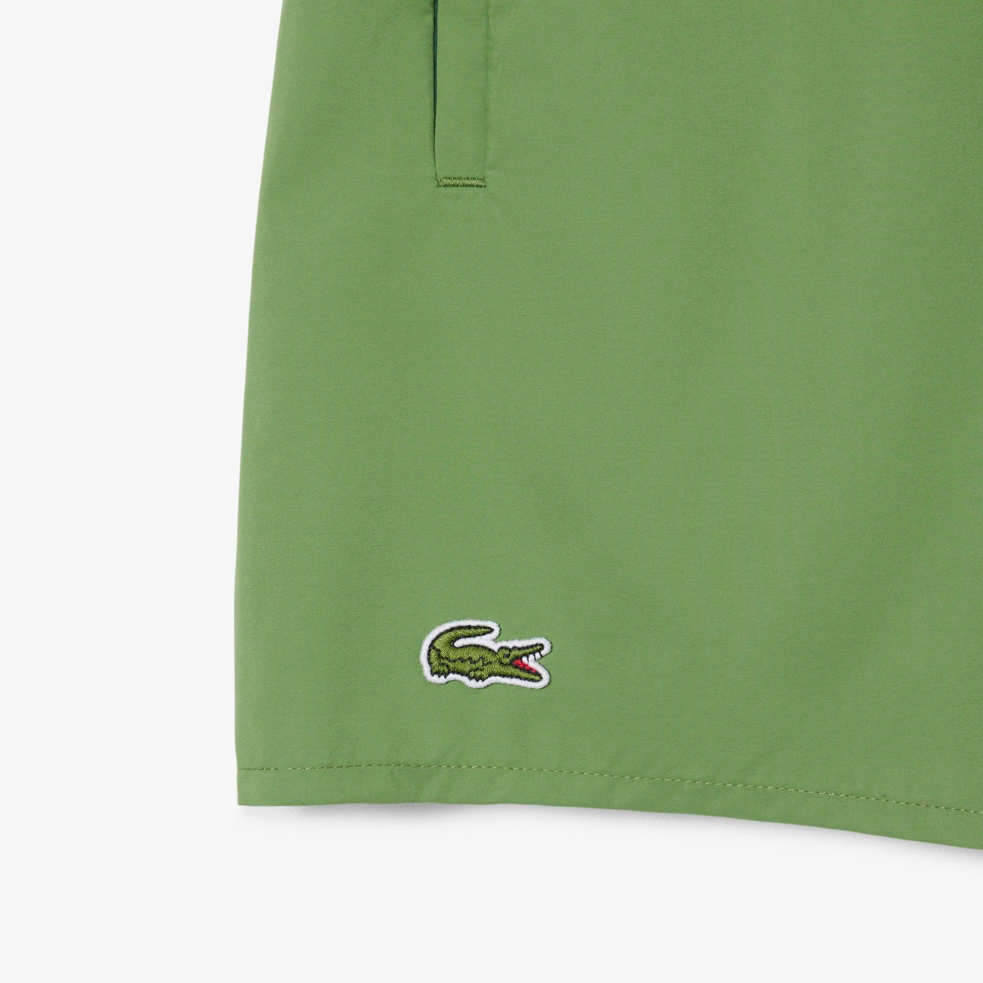 Dettaglio shorts verdi uomo con logo ricamato, tasca laterale, moda primavera estate.