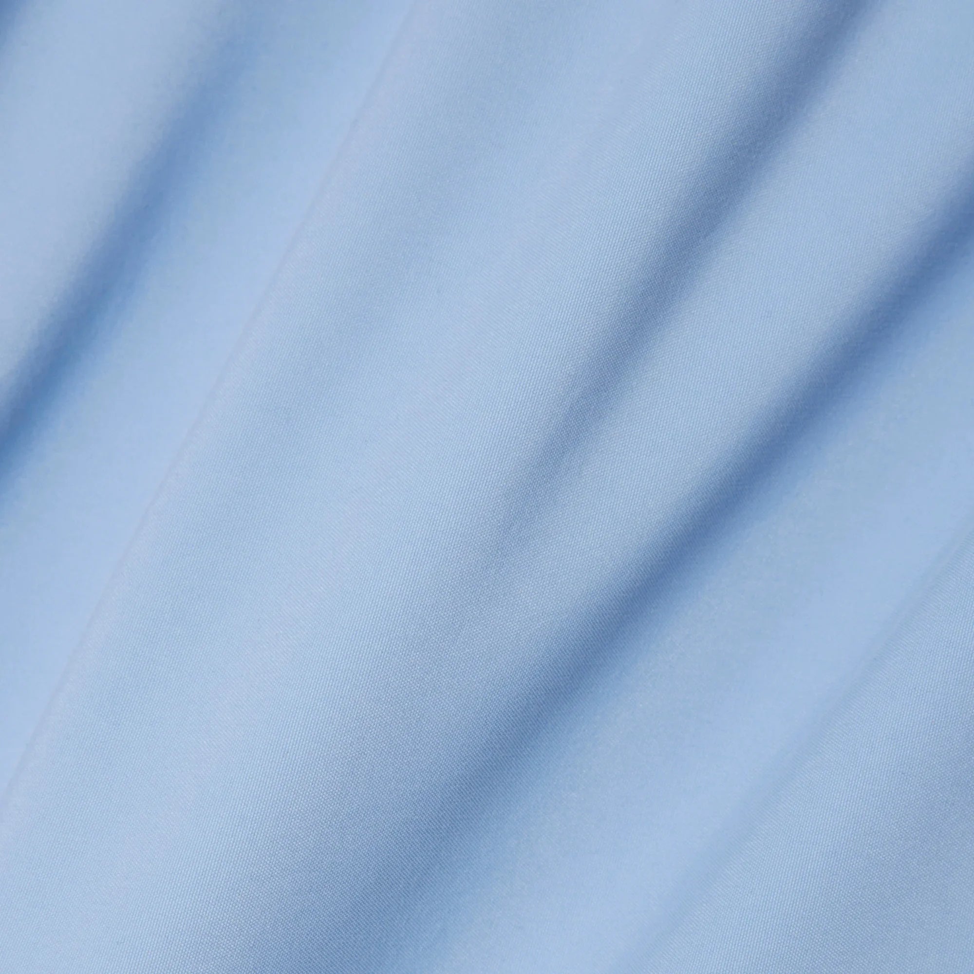 Dettaglio tessuto camicia azzurra in cotone, texture liscia e pieghe leggere