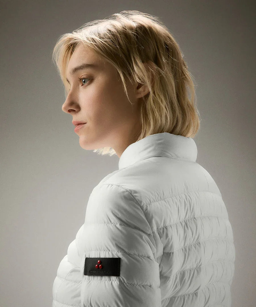 Donna con piumino bianco trapuntato, dettagli logo sulla manica, moda autunno inverno.