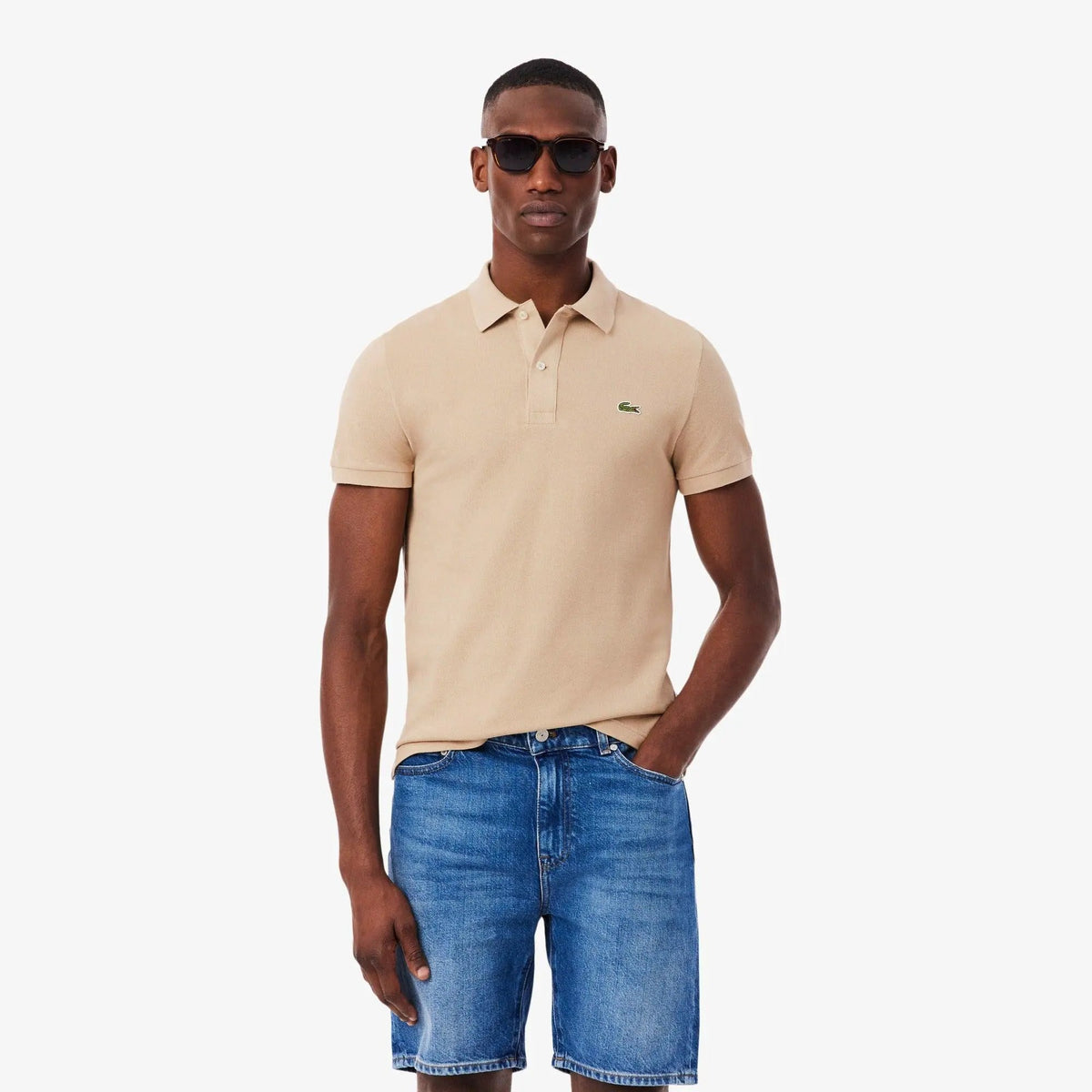Modello con polo beige e pantaloncini di jeans, stile casual uomo, abbigliamento estivo.