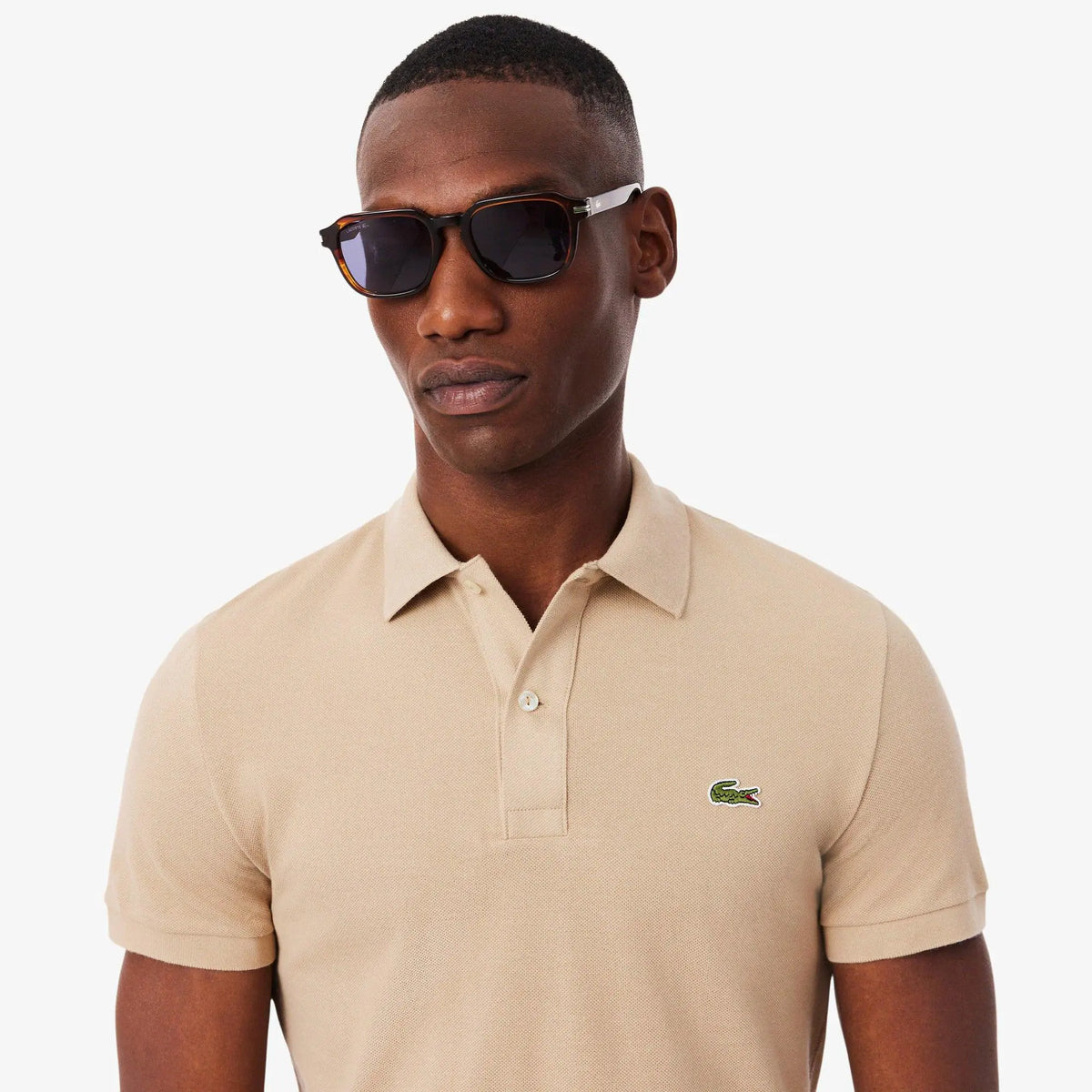 Uomo con polo beige a maniche corte e occhiali da sole, moda uomo elegante casual.