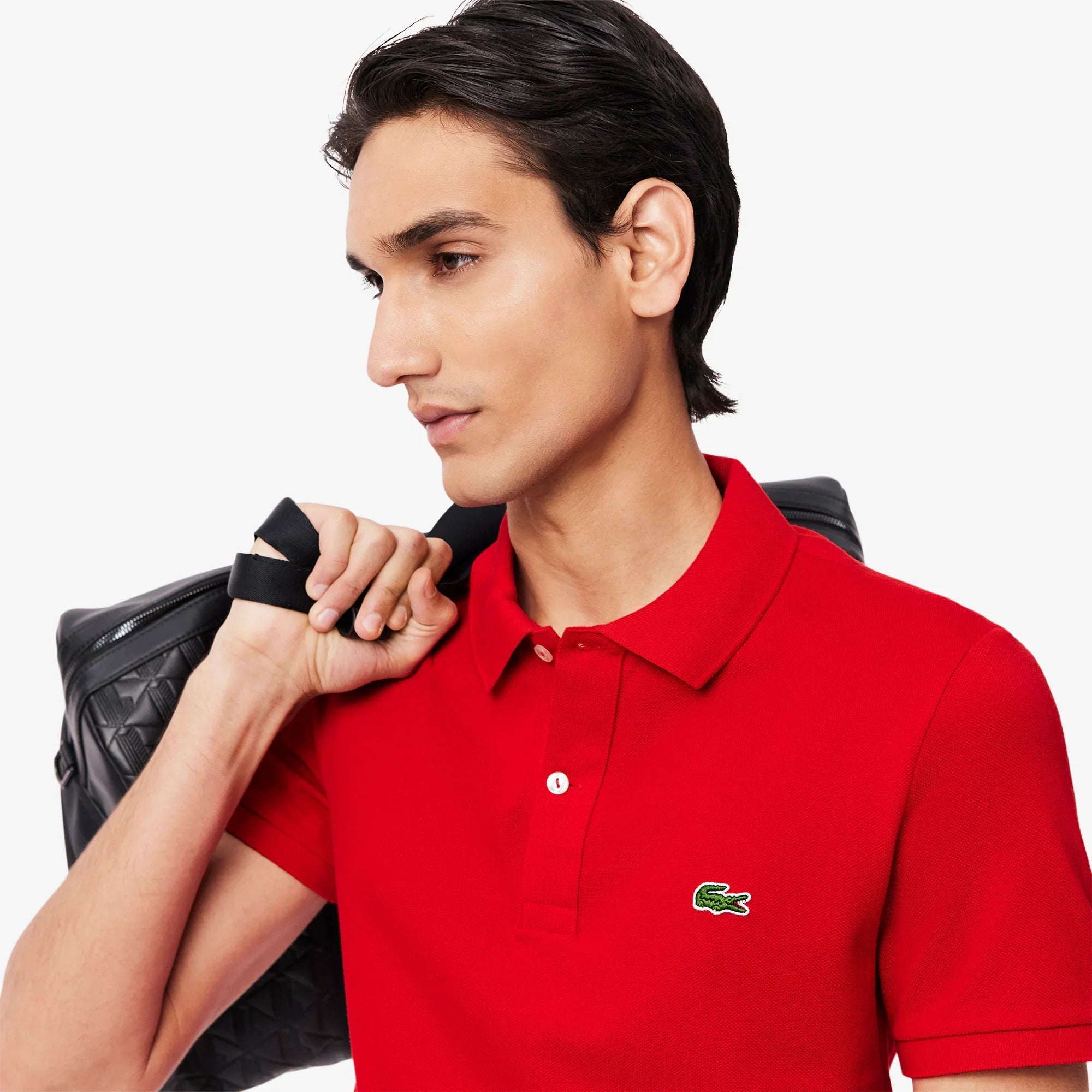Uomo con polo rossa in cotone, logo verde sul petto e borsa nera, moda uomo casual