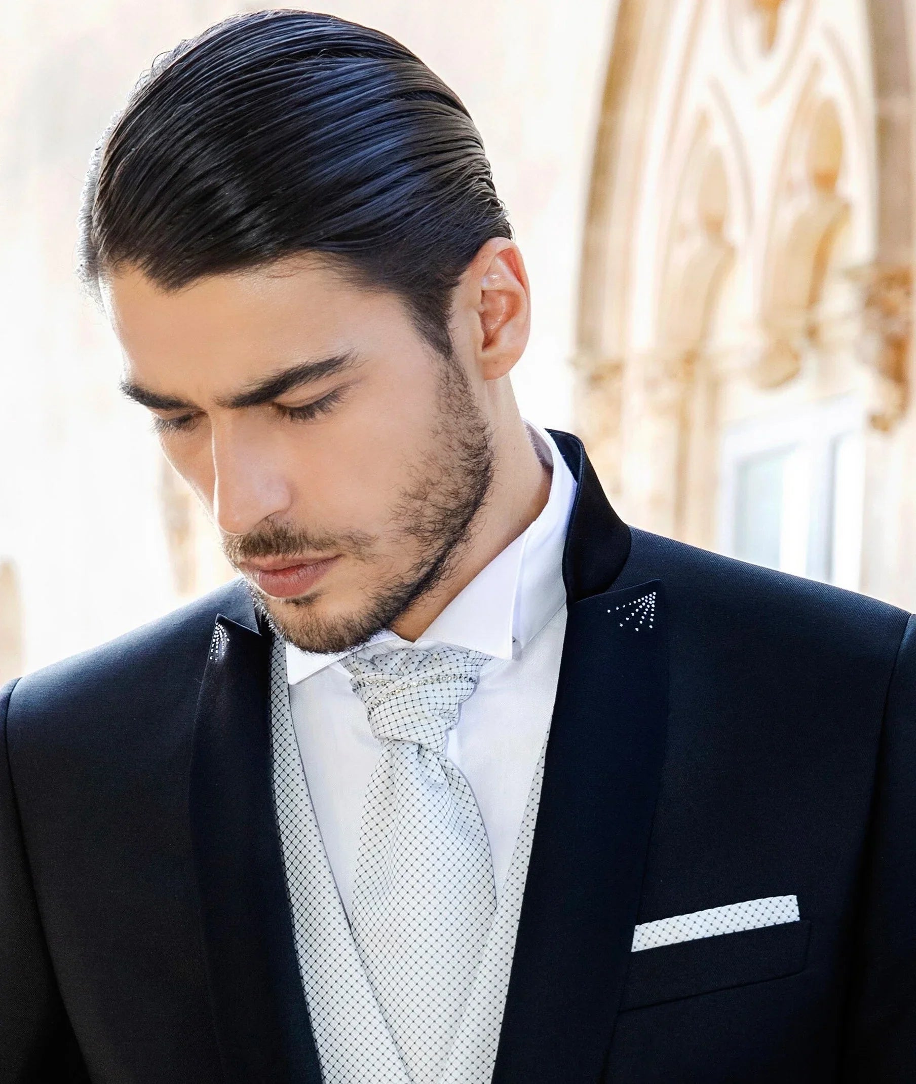 Uomo elegante in abito da cerimonia nero, gilet e cravatta chiara, moda uomo alta qualità.