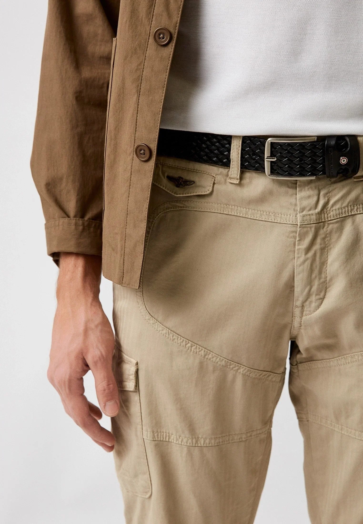 Pantaloni cargo uomo beige con cintura intrecciata nera e giacca marrone, stile casual elegante